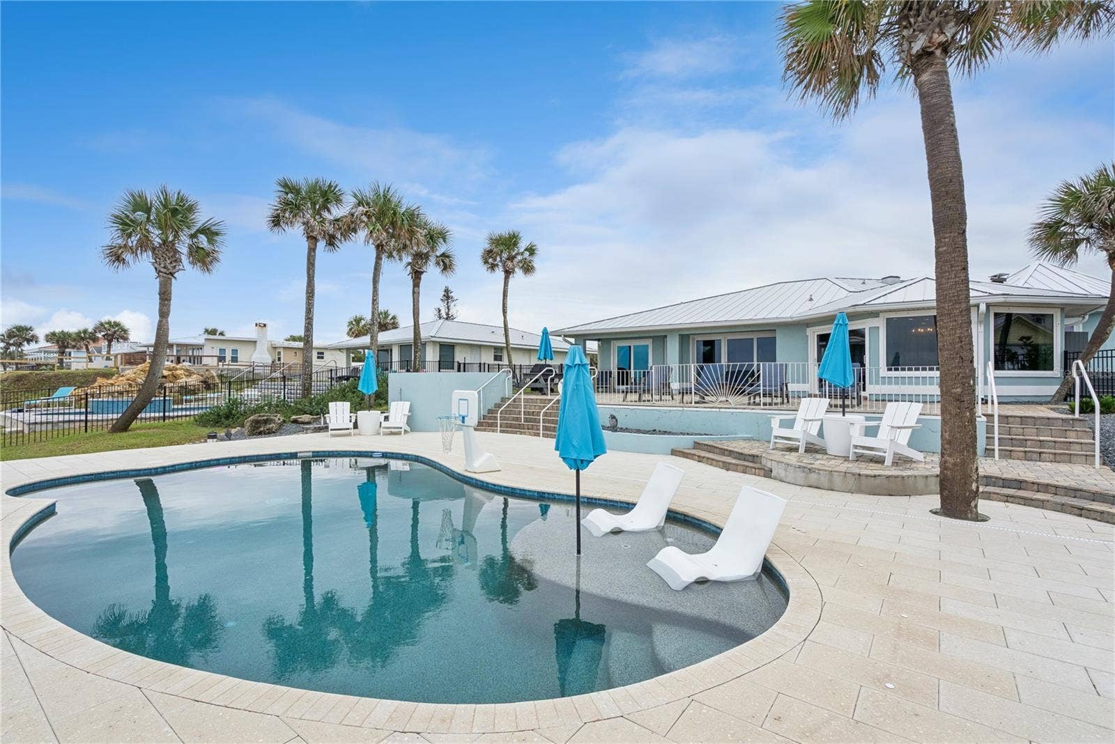 New oceanfront pool installed in 2024, featuring heating, a sun shelf, bubblers, and a 7-foot-deep end, with expansive patio space and panoramic Atlantic views.