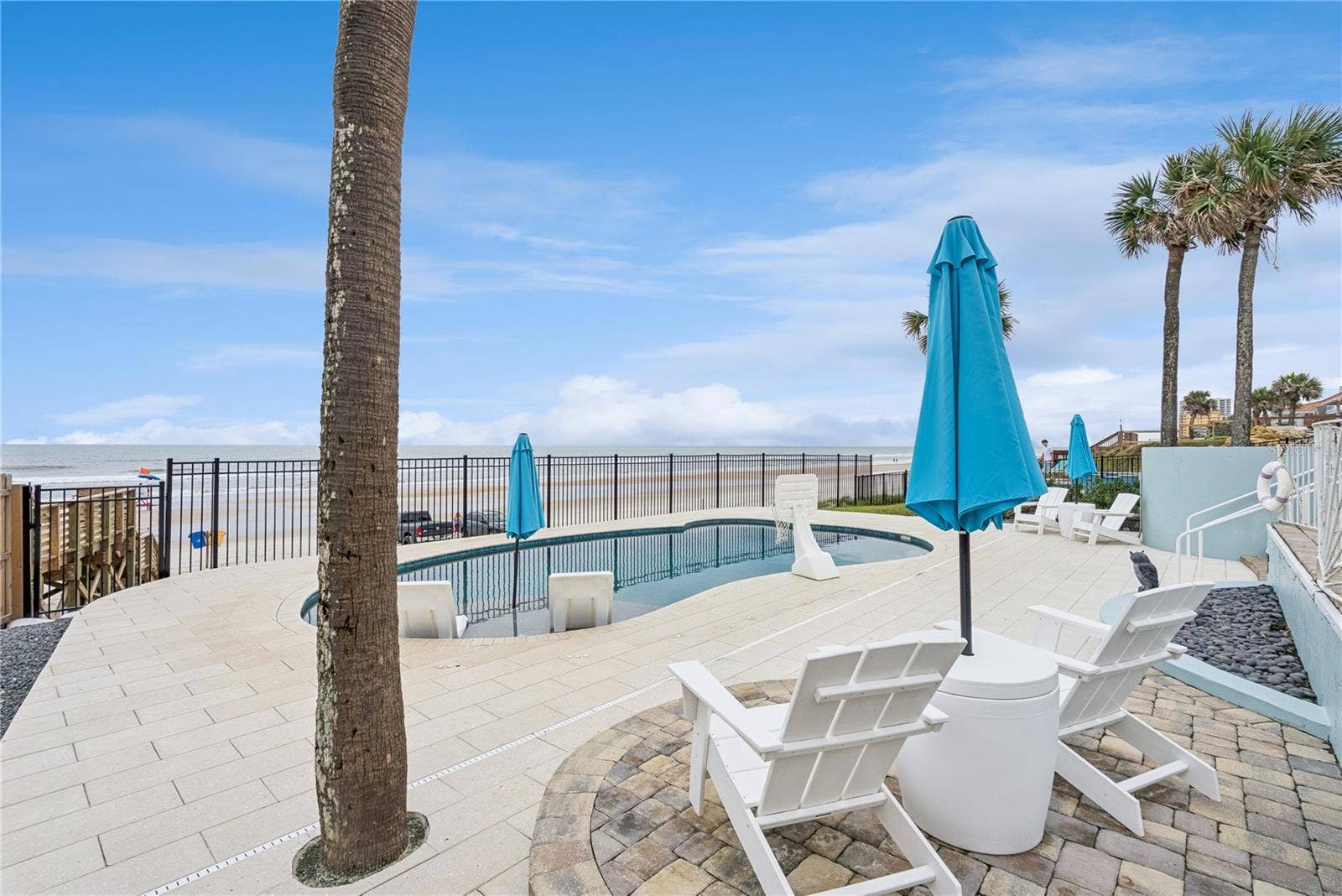 New oceanfront pool installed in 2024, featuring heating, a sun shelf, bubblers, and a 7-foot-deep end, with expansive patio space and panoramic Atlantic views.