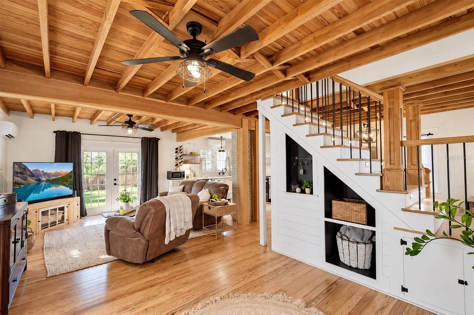 1901 10TH STREET, St Cloud, FL 34769 OPEN-CONCEPT LIVING SPACE featuring beautiful EXPOSED WOOD BEAM CEILINGS, hardwood floors, and custom BUILT-IN SHELVING AND STORAGE beneath the staircase. FRENCH DOORS provide abundant natural light and lead to the SPACIOUS, FULLY FENCED BACKYARD. The living area flows seamlessly into the OPEN KITCHEN, creating a wonderful space for everyday living and entertaining!