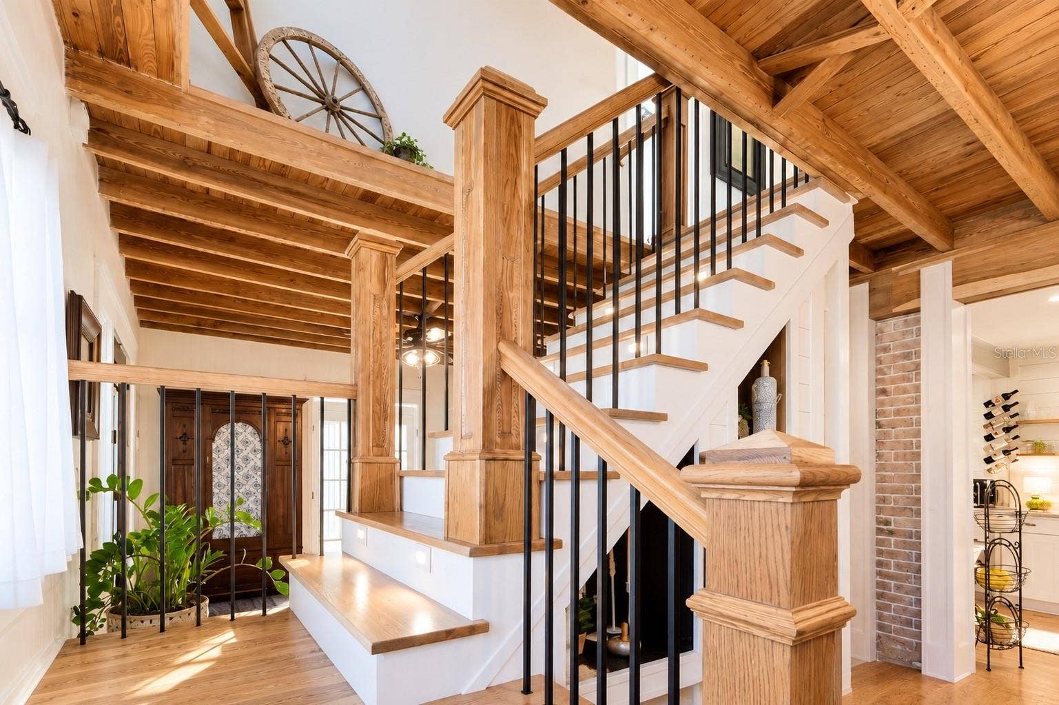 1901 10TH STREET, St Cloud, FL 34769 Beautiful custom wood staircase featuring rich wood posts and handrails, contrasting black iron balusters, and exposed wood beam ceilings that add warmth and architectural character throughout the home.