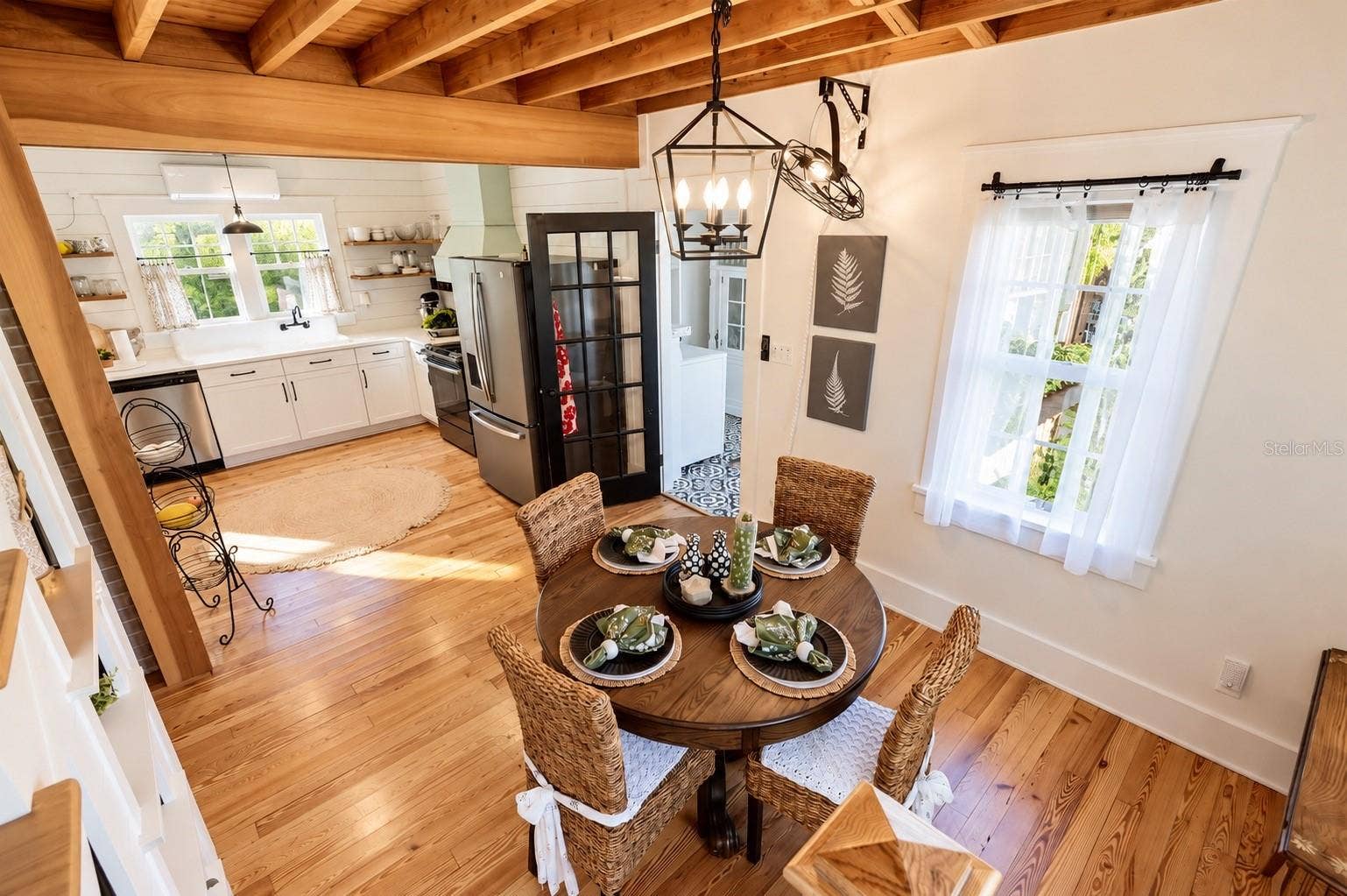 1901 10TH STREET, St Cloud, FL 34769 FARMHOUSE-STYLE DINING AREA featuring gorgeous exposed wood beam ceilings, beautiful wood flooring, a stylish lantern chandelier, and abundant natural light! OPEN TO THE BEAUTIFULLY UPDATED KITCHEN, creating a warm and inviting space for everyday dining and entertaining.