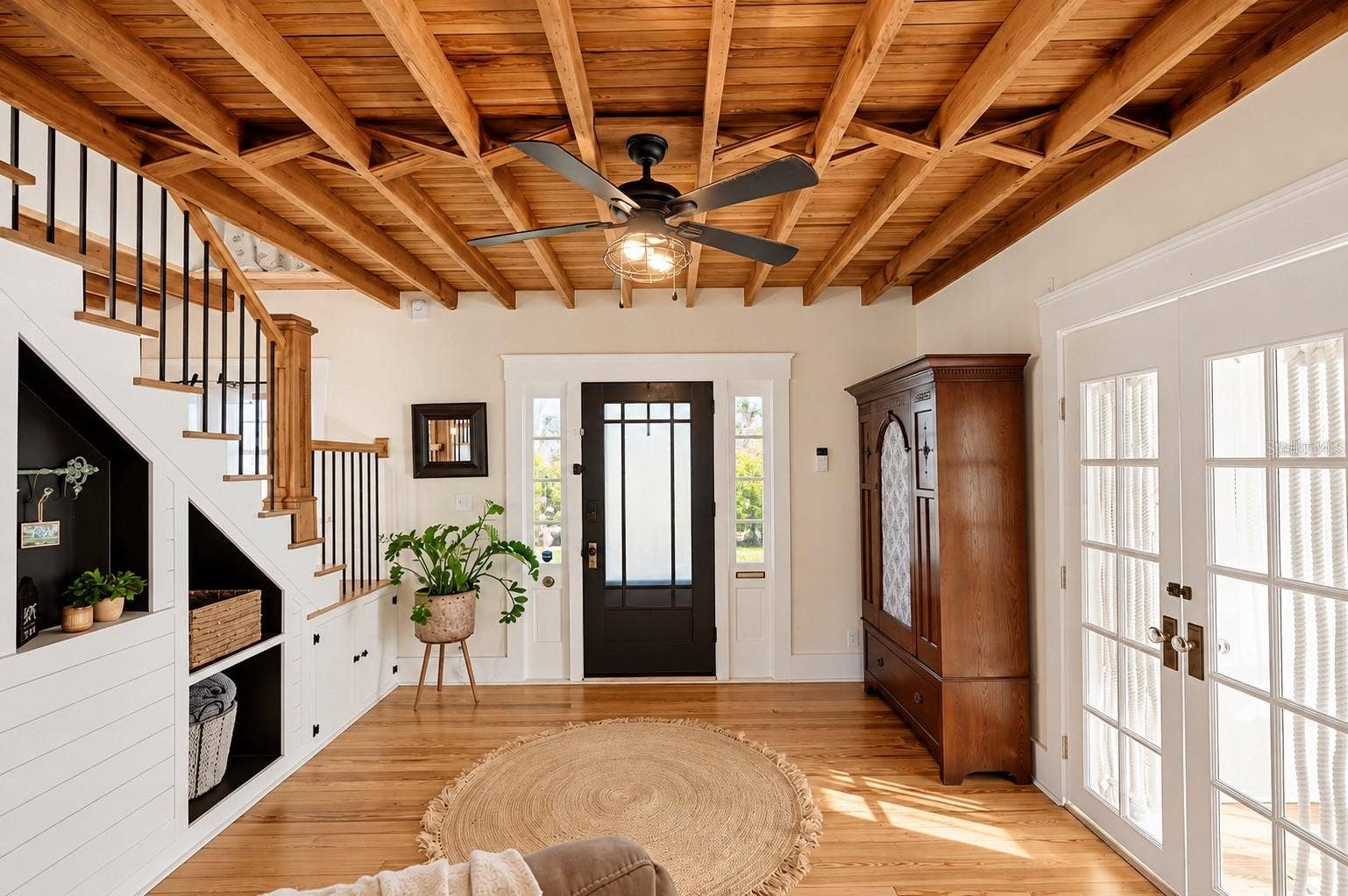 1901 10TH STREET, St Cloud, FL 34769 CHARMING ENTRYWAY featuring stunning EXPOSED WOOD BEAM CEILINGS, beautiful hardwood floors, a wooden staircase with black iron balusters, custom built-in shelving and storage, and French doors that fill the space with natural light.