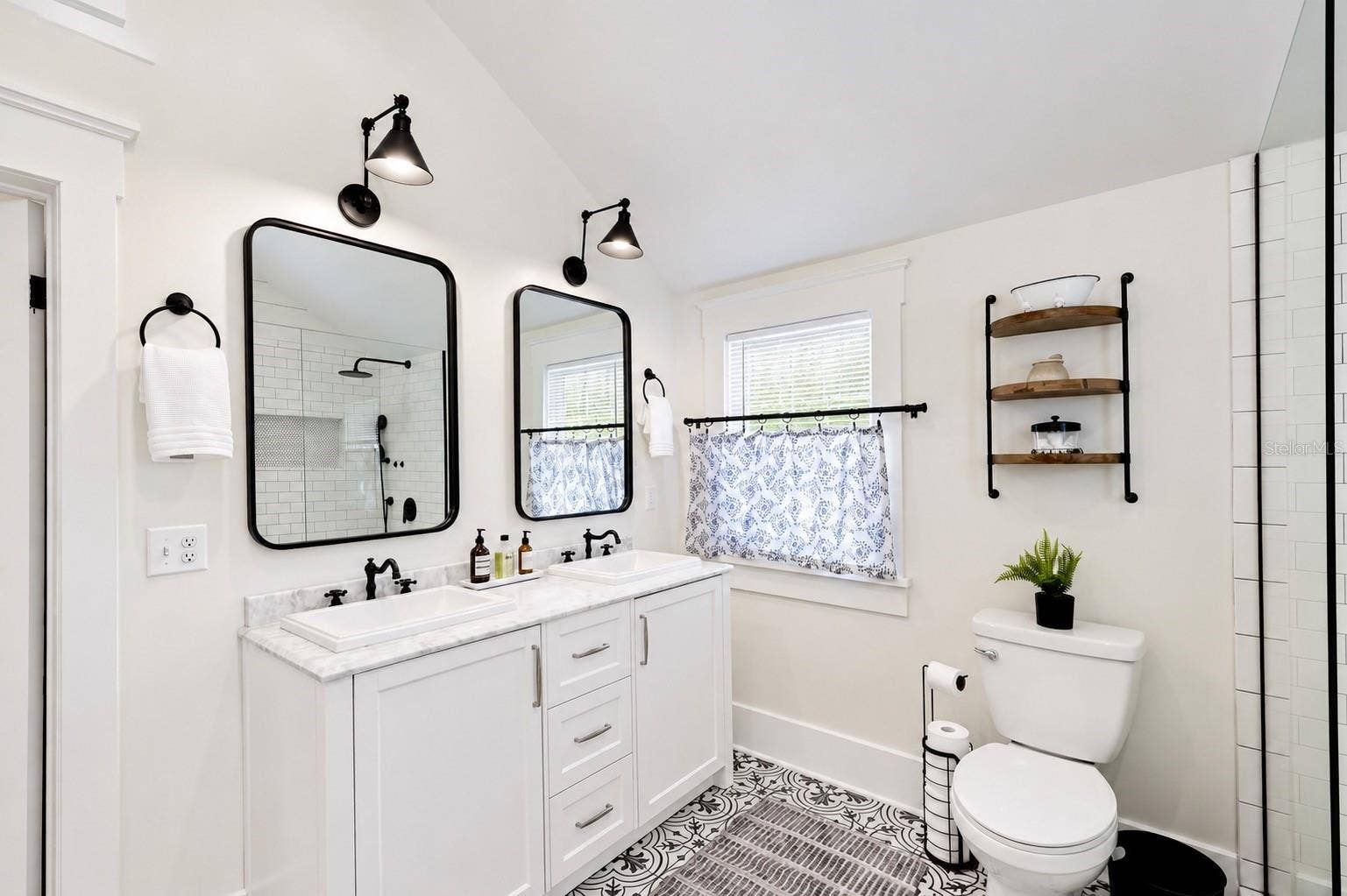 1901 10TH STREET, St Cloud, FL 34769 Beautifully updated upstairs bathroom featuring a spacious DOUBLE-SINK VANITY with marble-look countertops, stylish black fixtures, individual mirrors and lighting, ample cabinet storage, and gorgeous patterned tile flooring. Conveniently located between both upstairs bedrooms.