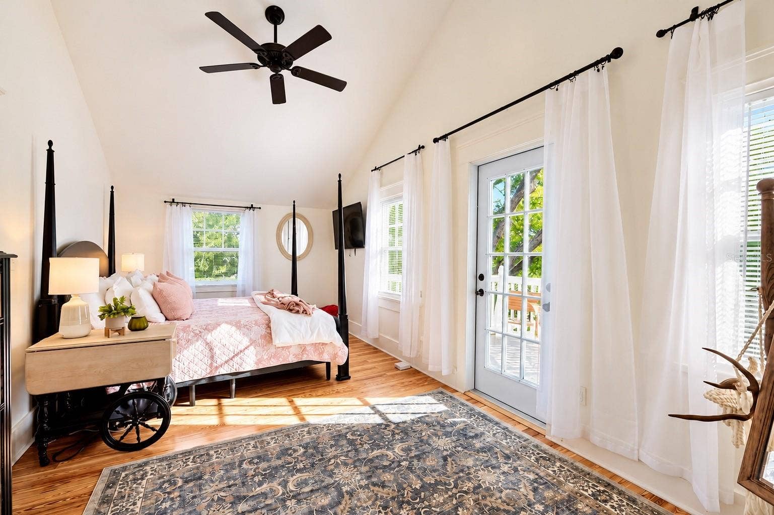 1901 10TH STREET, St Cloud, FL 34769 Bright and spacious bedroom featuring vaulted ceilings, beautiful hardwood floors, abundant natural light, and French doors leading to the outdoor deck.