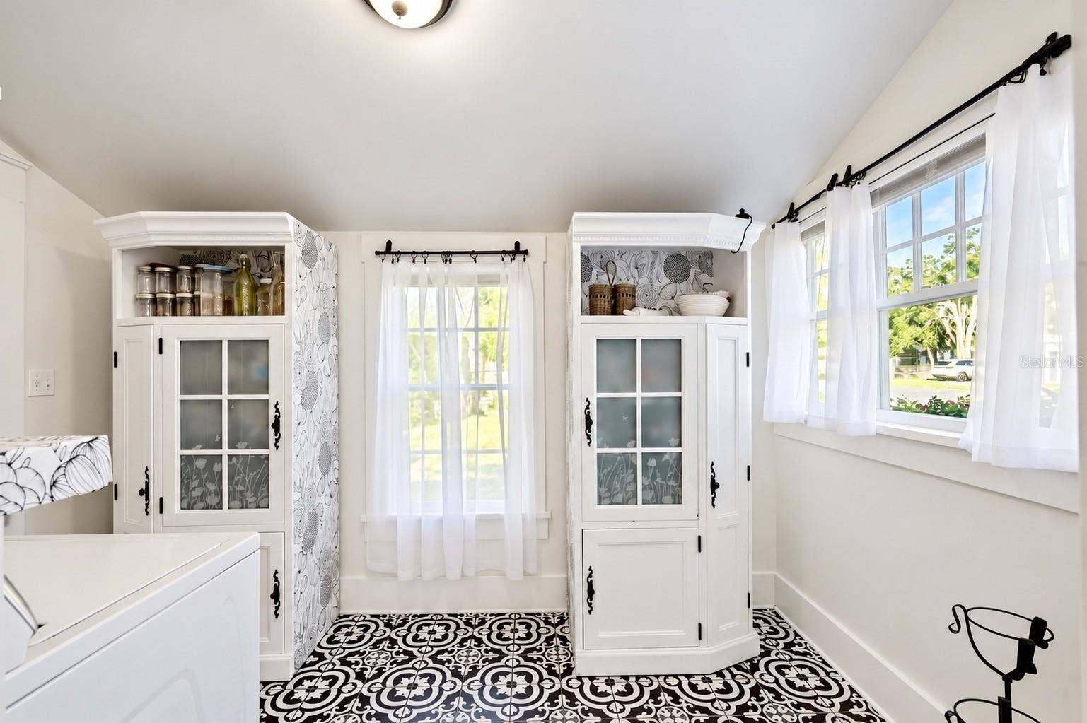 1901 10TH STREET, St Cloud, FL 34769 INDOOR LAUNDRY ROOM featuring beautiful patterned tile flooring, abundant natural light, and decorative storage cabinets. Convenient access through the adjoining full downstairs bathroom leads to the spacious FENCED BACKYARD AND BARN, offering both functionality and farmhouse charm!