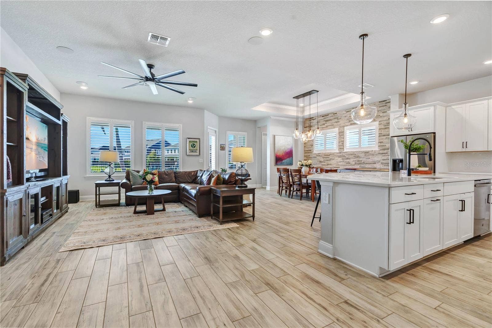 8336 CANETTI STREET, Orlando, FL 32827 Open floor plan connecting the great room, kitchen, and dining area. Wood look plank tile, crown moulding, and natural light throughout this one story Lake Nona home.