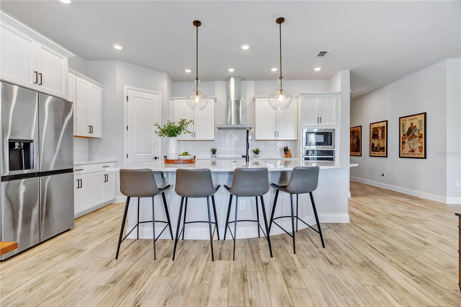 8336 CANETTI STREET, Orlando, FL 32827 Chef inspired kitchen with an expansive Calacatta Arno quartz island, seating for four, statement pendants, stainless appliances, and a built in wall oven and microwave.