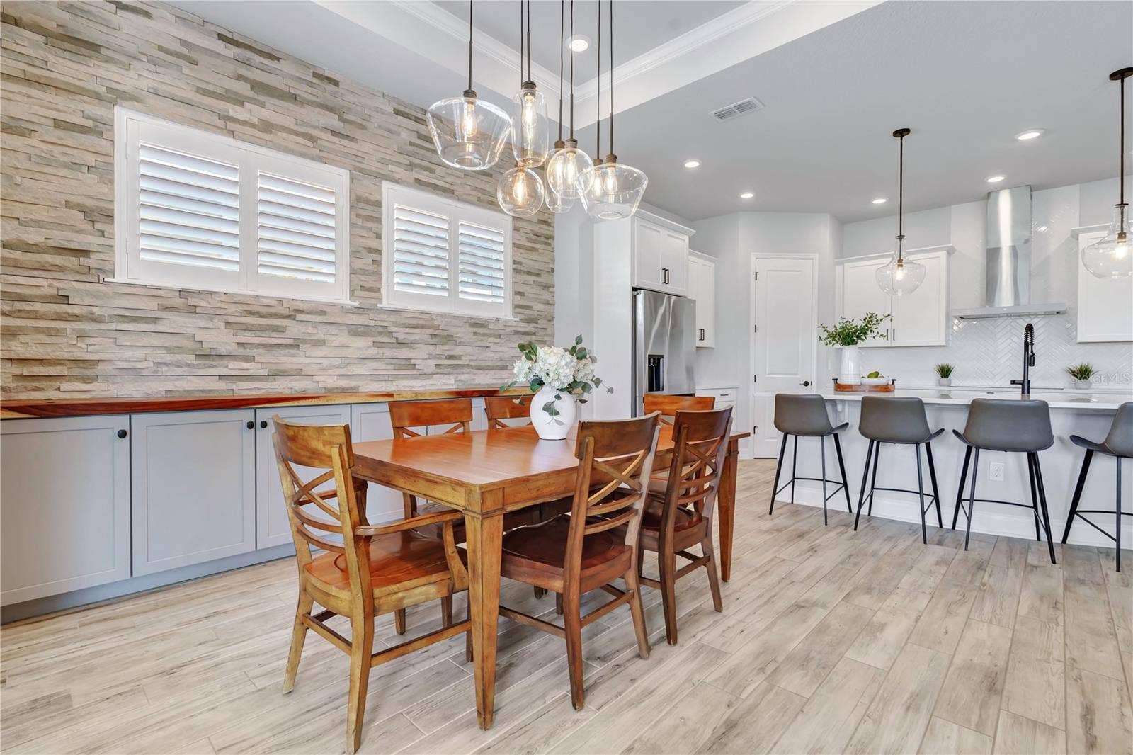 8336 CANETTI STREET, Orlando, FL 32827 Dining area with a stone accent wall and modern chandelier, steps from the kitchen. Ideal for dinners at home in Lake Nona.