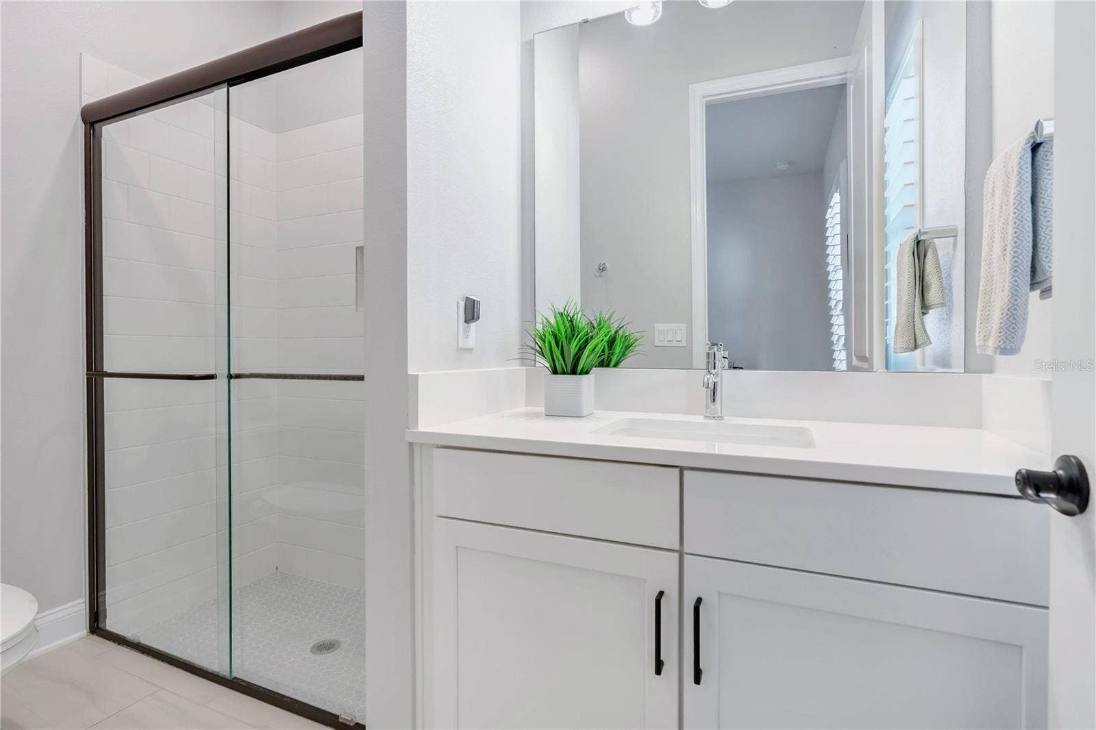 8336 CANETTI STREET, Orlando, FL 32827 Secondary bath with walk in shower with tile to the ceiling, ceiling mounted rain shower head, and hex mosaic floor.