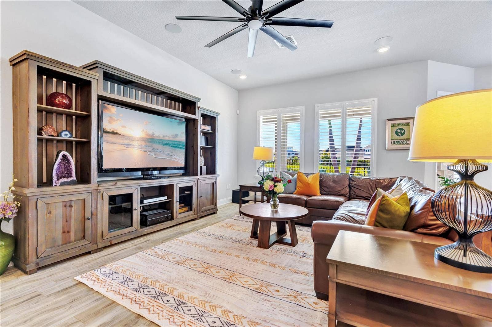 8336 CANETTI STREET, Orlando, FL 32827 Spacious family room with a custom entertainment wall and wood look plank tile, flowing into the kitchen and dining area.