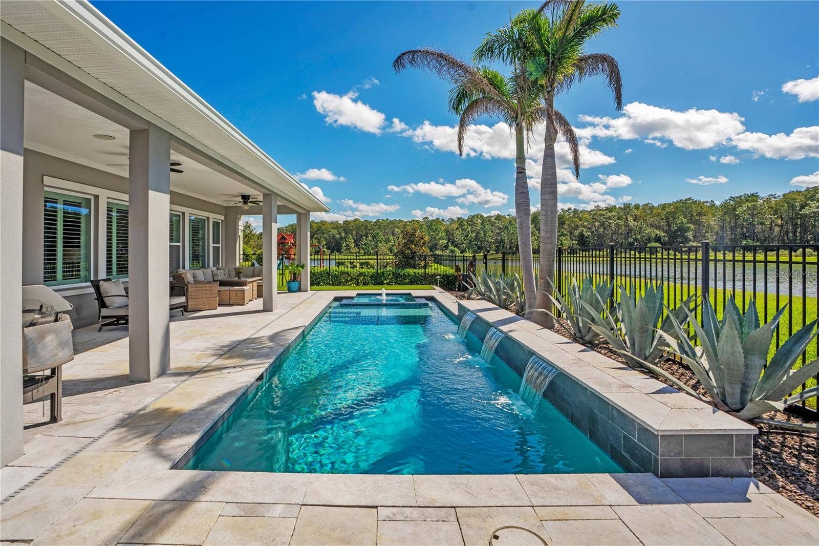 8336 CANETTI STREET, Orlando, FL 32827 Heated salt water pool viewed from the covered lanai with palms and a water view.