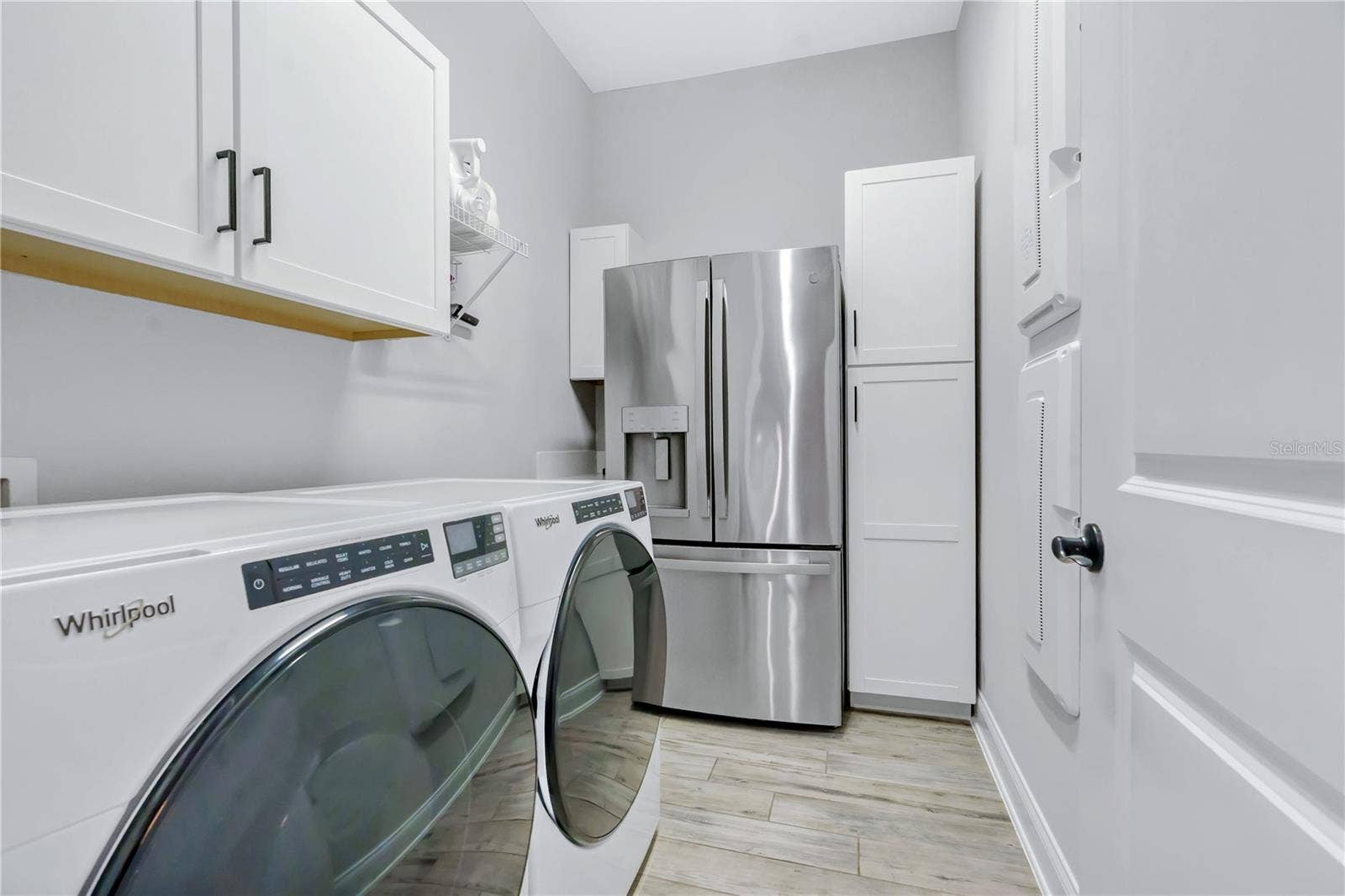 8336 CANETTI STREET, Orlando, FL 32827 Laundry room with storage cabinetry and space for a second refrigerator, plus a mud room drop zone near the entry.