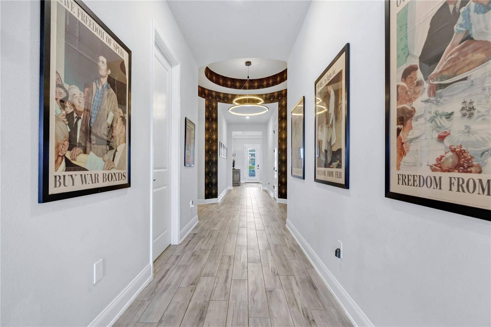8336 CANETTI STREET, Orlando, FL 32827 Gallery style entry hallway with wood look plank tile, wide baseboards, and crown moulding welcoming you inside.