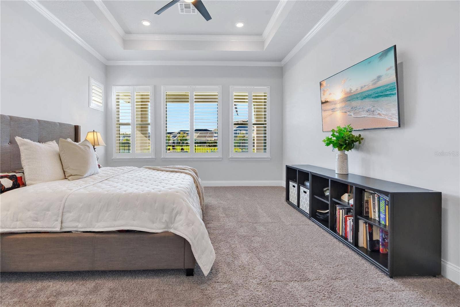 8336 CANETTI STREET, Orlando, FL 32827 Primary bedroom with tray ceiling, ceiling fan, and plantation shutters.