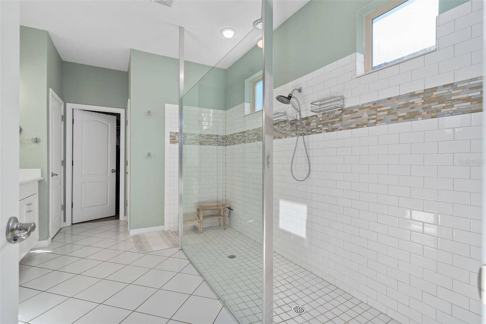 1038 TIMBERVALE TRAIL, Clermont, FL 34715 Primary En-Suite Shower with a hand held sprayer and a Rain Shower. The Subway tile is accented with a beautiful Listello
