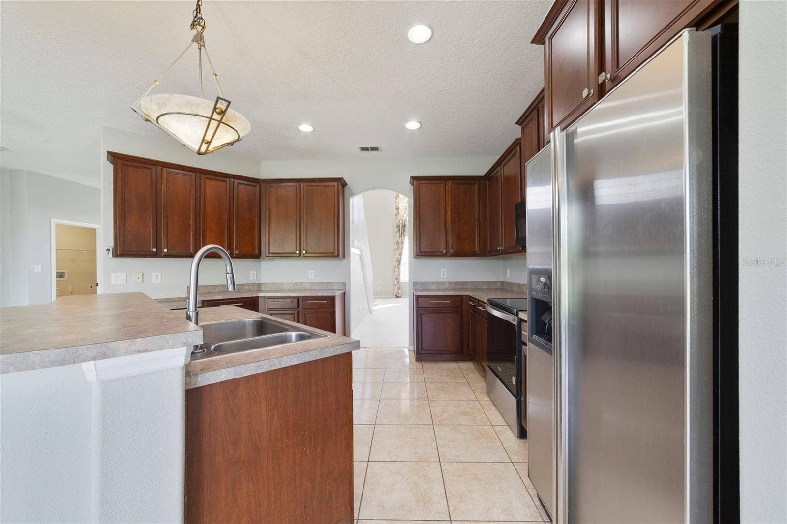 1557 AMARYLLIS CIRCLE, Orlando, FL 32825 Step through an arched doorway into the spacious Kitchen with ABUNDANT STAGGERED CABINETRY and generous counter space.