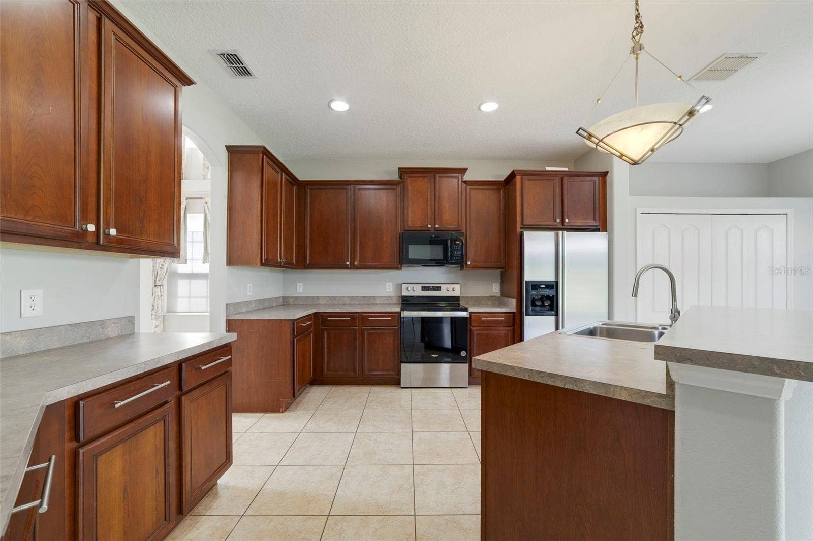 1557 AMARYLLIS CIRCLE, Orlando, FL 32825 Step through an arched doorway into the spacious Kitchen with ABUNDANT STAGGERED CABINETRY and generous counter space.