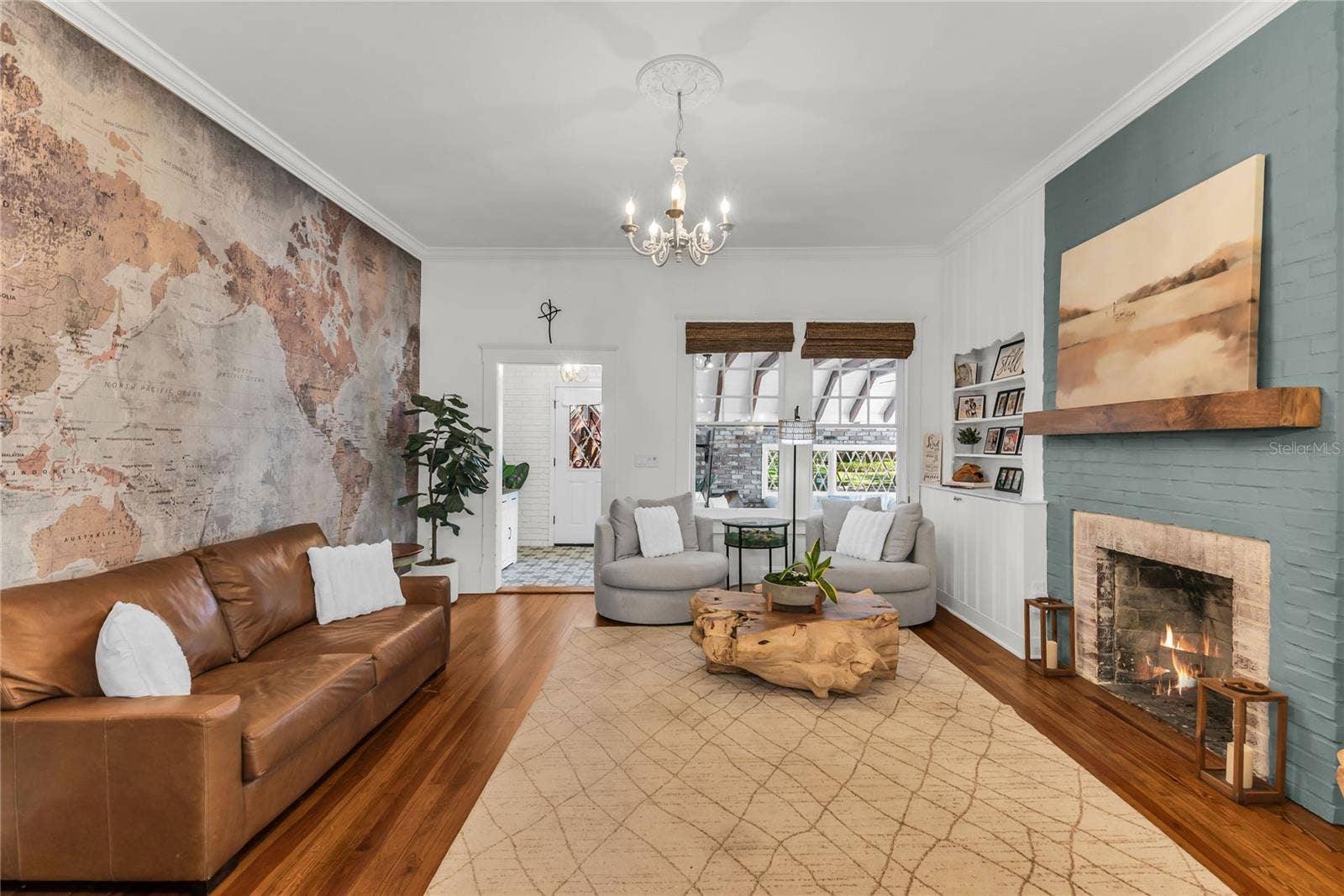 234 N LAKEVIEW AVENUE, Winter Garden, FL 34787 The warm and welcoming Formal Living Room is anchored by a wood-burning brick fireplace accented by a substantial wood mantle and custom painted brick. A custom built in shelf, original wood flooring and chandelier preserve the homes original historic charm and a world map accent wall adds personality. The spacious layout offers a seamless connection to the adjoining dining room and kitchen, creating an effortless flow throughout the home's main living spaces.