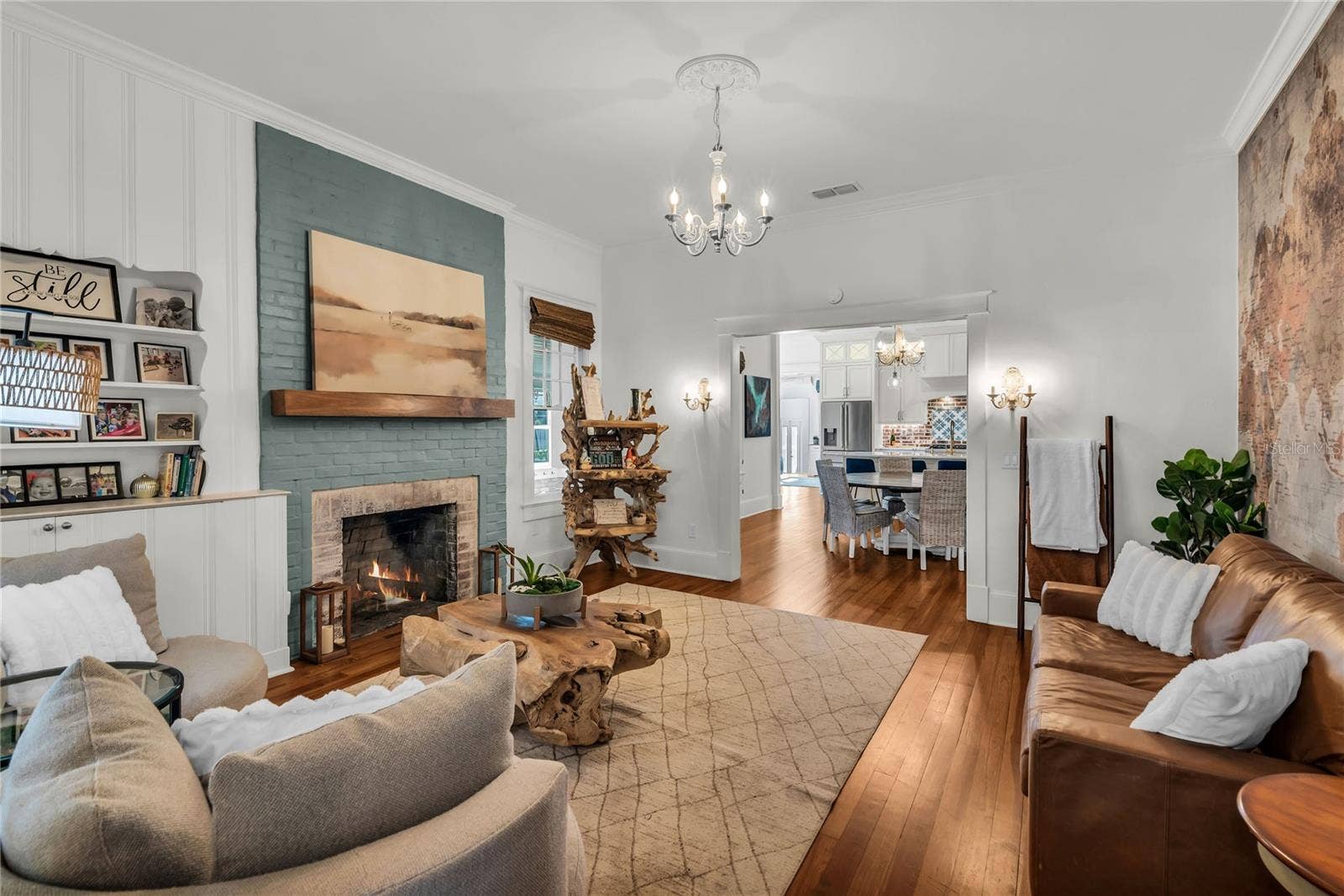 234 N LAKEVIEW AVENUE, Winter Garden, FL 34787 The warm and welcoming Formal Living Room is anchored by a wood-burning brick fireplace accented by a substantial wood mantle and custom painted brick. A custom built in shelf, original wood flooring and chandelier preserve the homes original historic charm and a world map accent wall adds personality. The spacious layout offers a seamless connection to the adjoining dining room and kitchen, creating an effortless flow throughout the home's main living spaces.