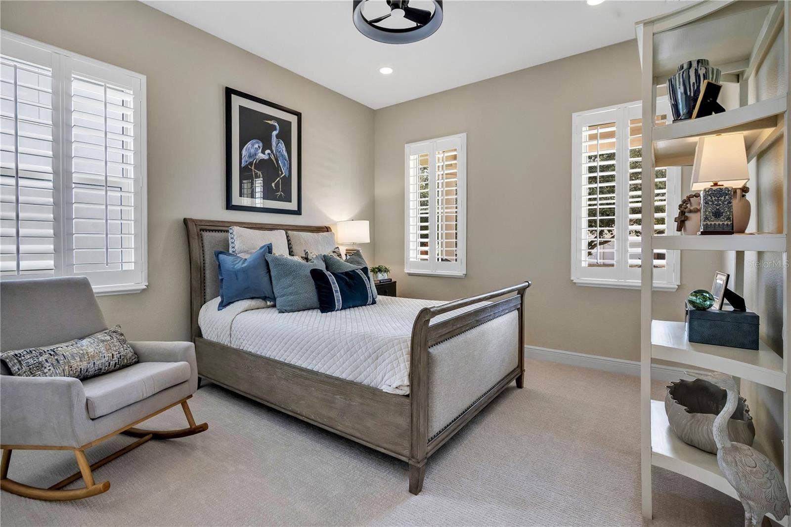 15749 CUTTER SAIL PLACE, Winter Garden, FL 34787 Inviting bedroom with plantation shutters and natural light from multiple windows.