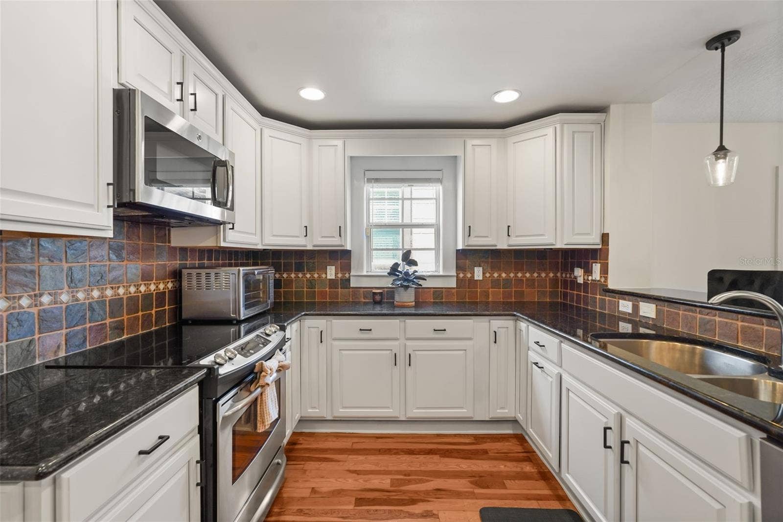 Kitchen with white cabinetry, stainless steel appliances, and tile backsplash