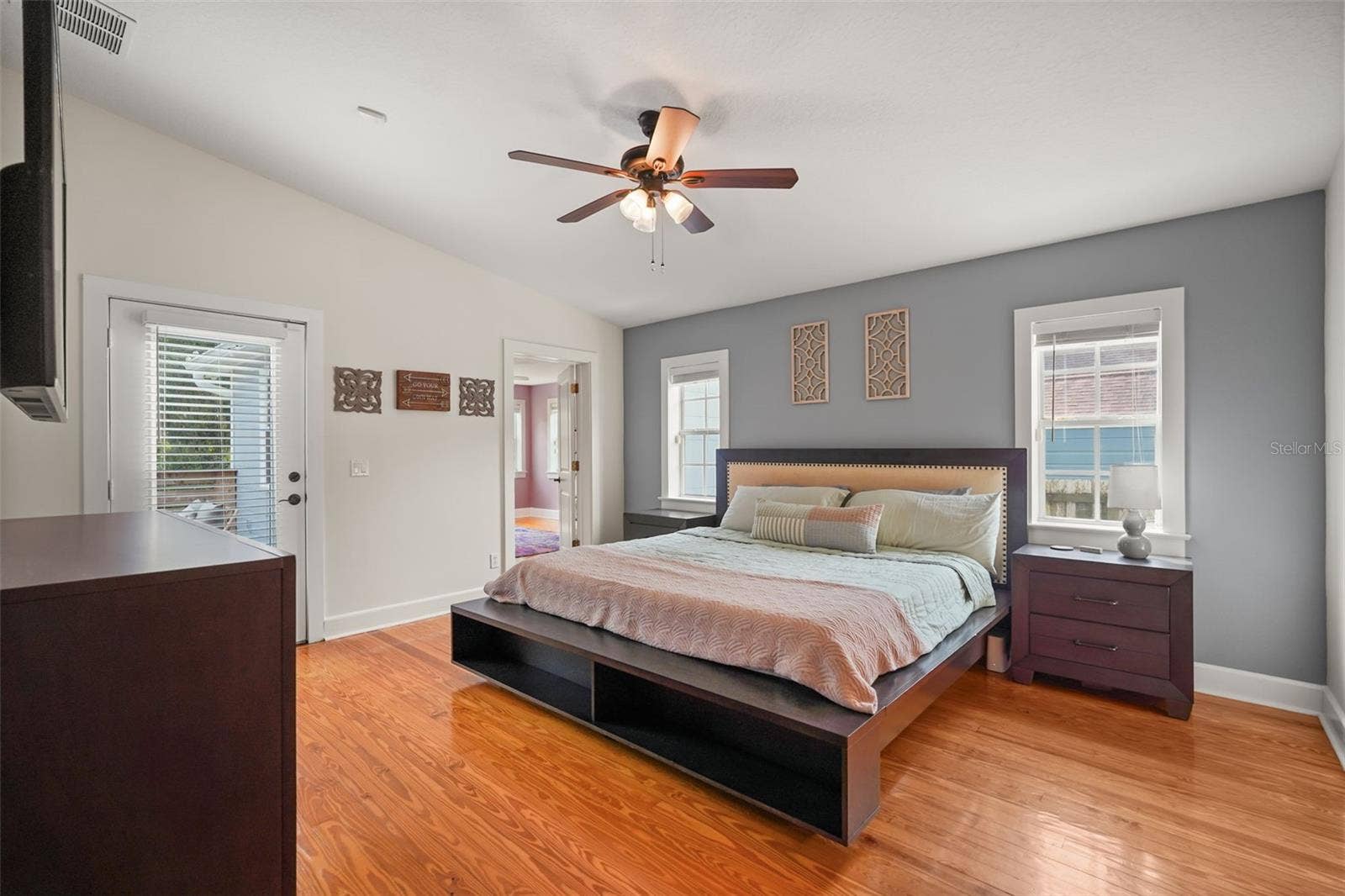 Primary bedroom with wood floors and door to the rear deck