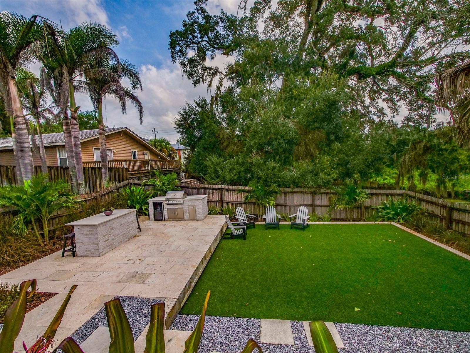 Backyard with outdoor kitchen, turf, and mature tree canopy