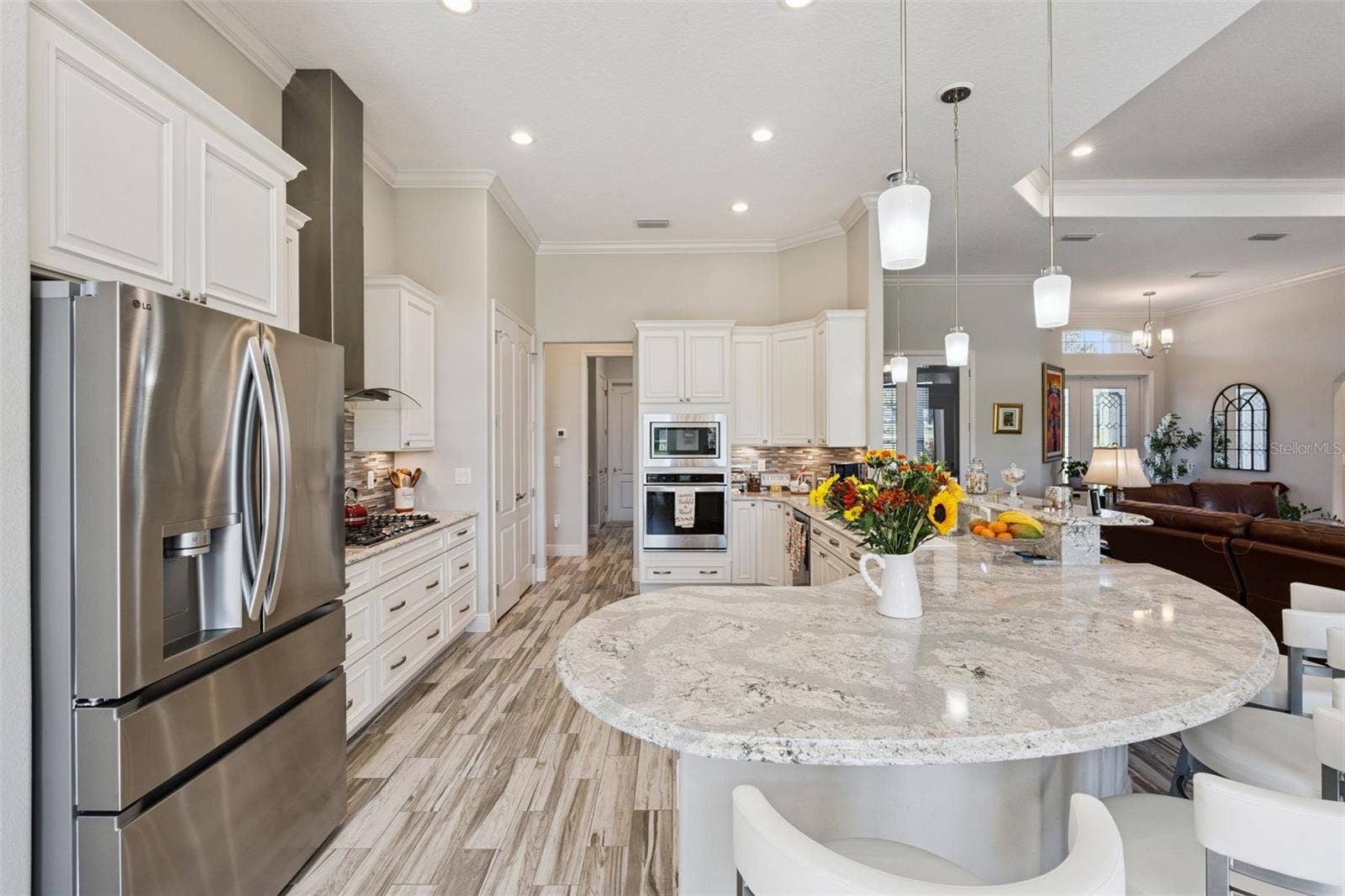 36819 WOLF COURT, Eustis, FL 32736 Designer kitchen featuring high-end stainless steel appliances, including a professional-grade gas cooktop, built-in wall oven, and a sleek modern vent hood.