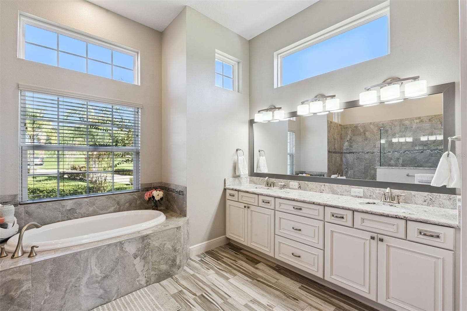 36819 WOLF COURT, Eustis, FL 32736 Light-filled primary en suite featuring elegant oversized windows, high-end lighting fixtures, and sleek quartz countertops.