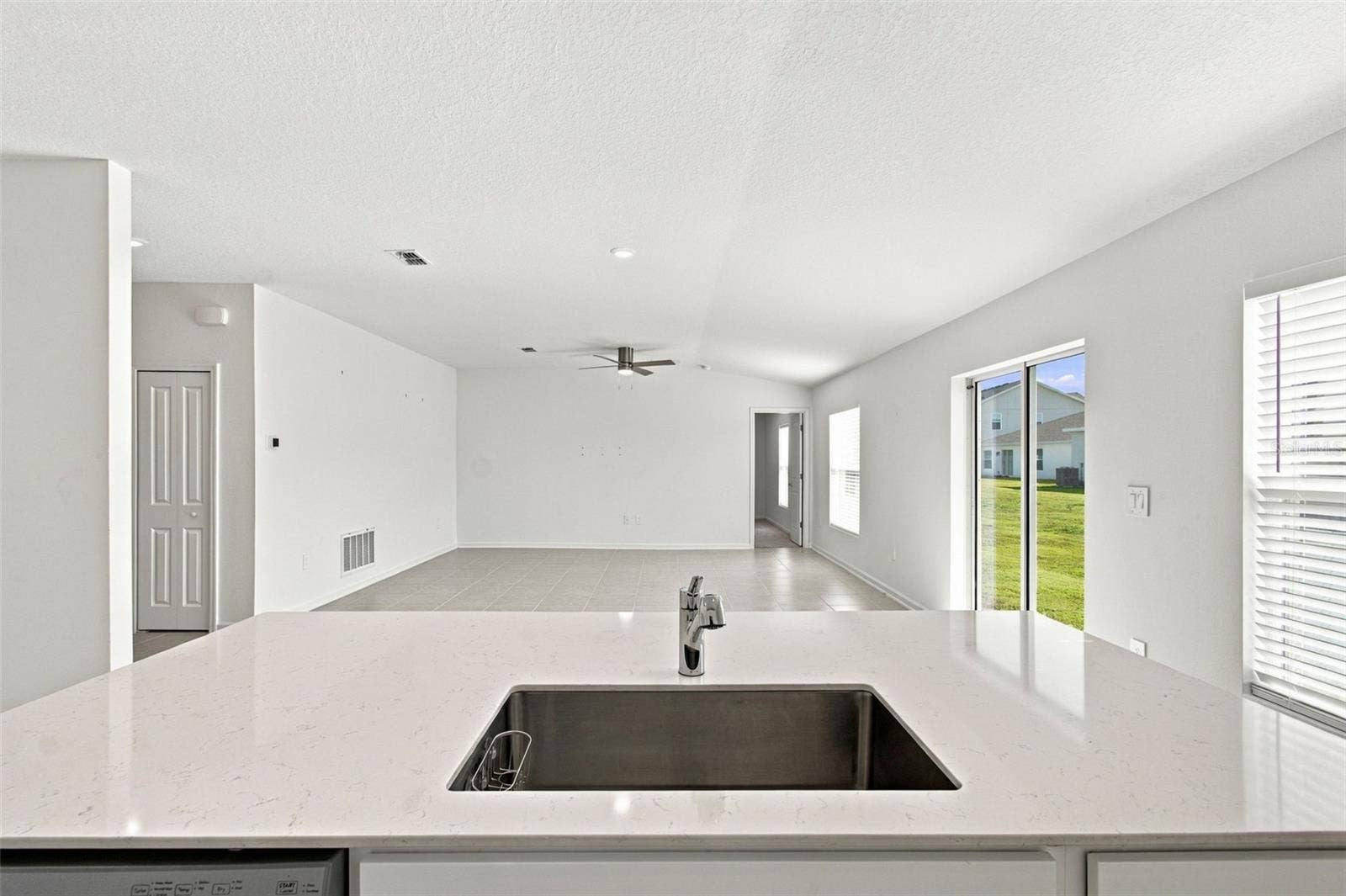The kitchen offers a spacious island with breakfast bar, white Shaker-style cabinetry, and quartz countertops, all overlooking the dining and living areas.