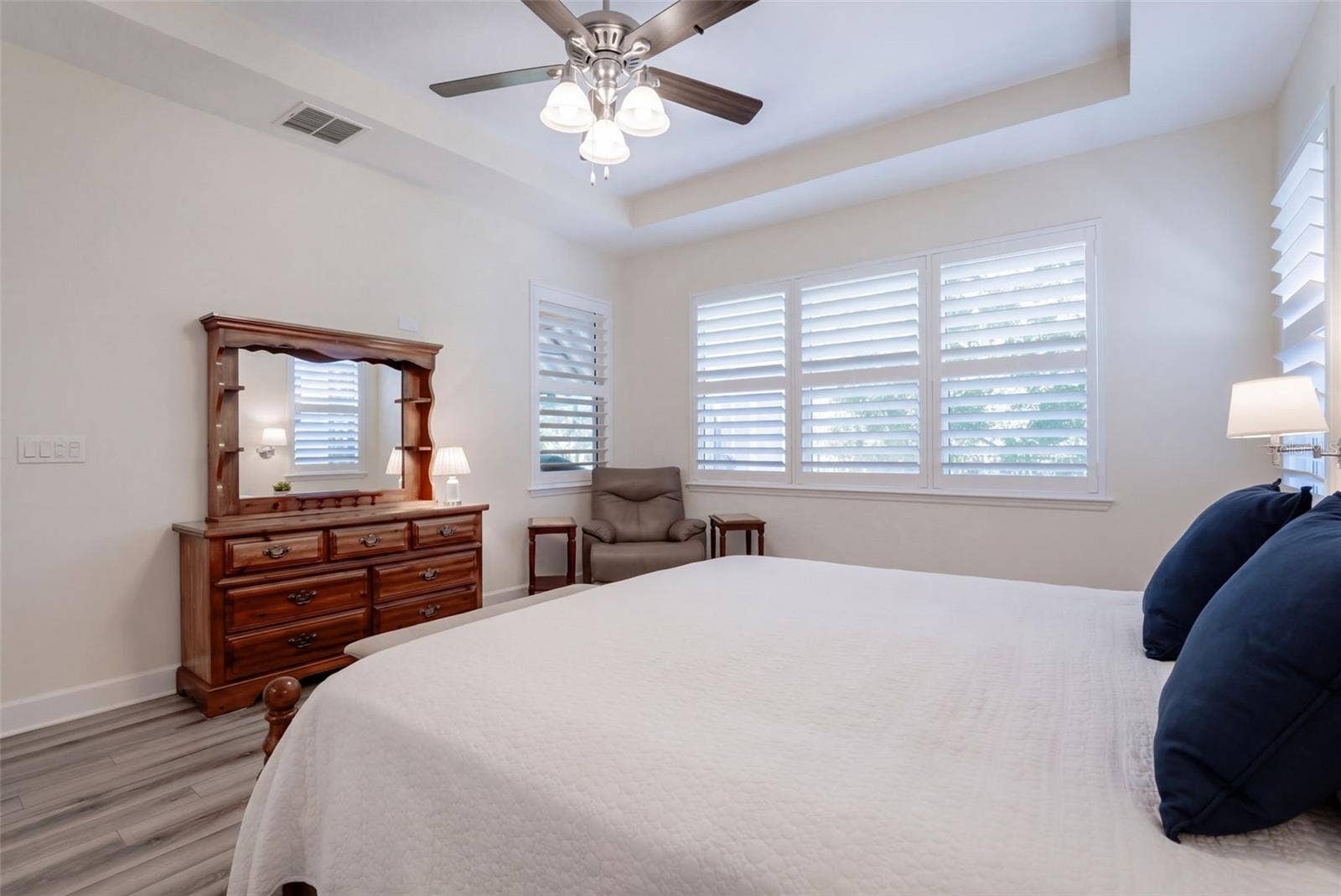 1233 EGGLESTON DRIVE, Deland, FL 32724 Primary Bedroom w/ Plantation style shutters, luxury vinyl floor, ceiling fan & a wooded view
