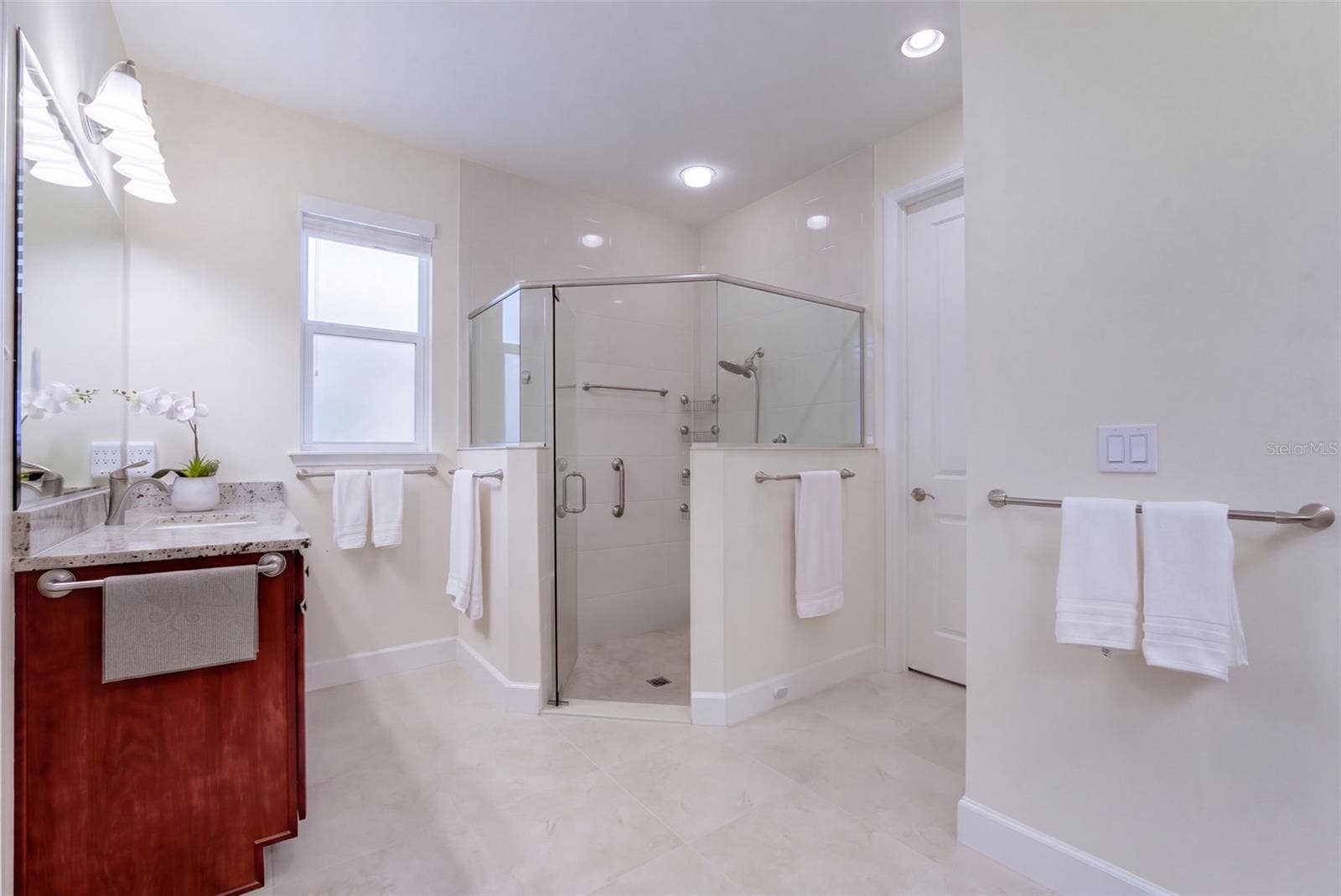 1233 EGGLESTON DRIVE, Deland, FL 32724 Primary Bathroom w/ separate granite vanities, glass enclosed walk-in shower, bench seat & a spacious walk-in closet