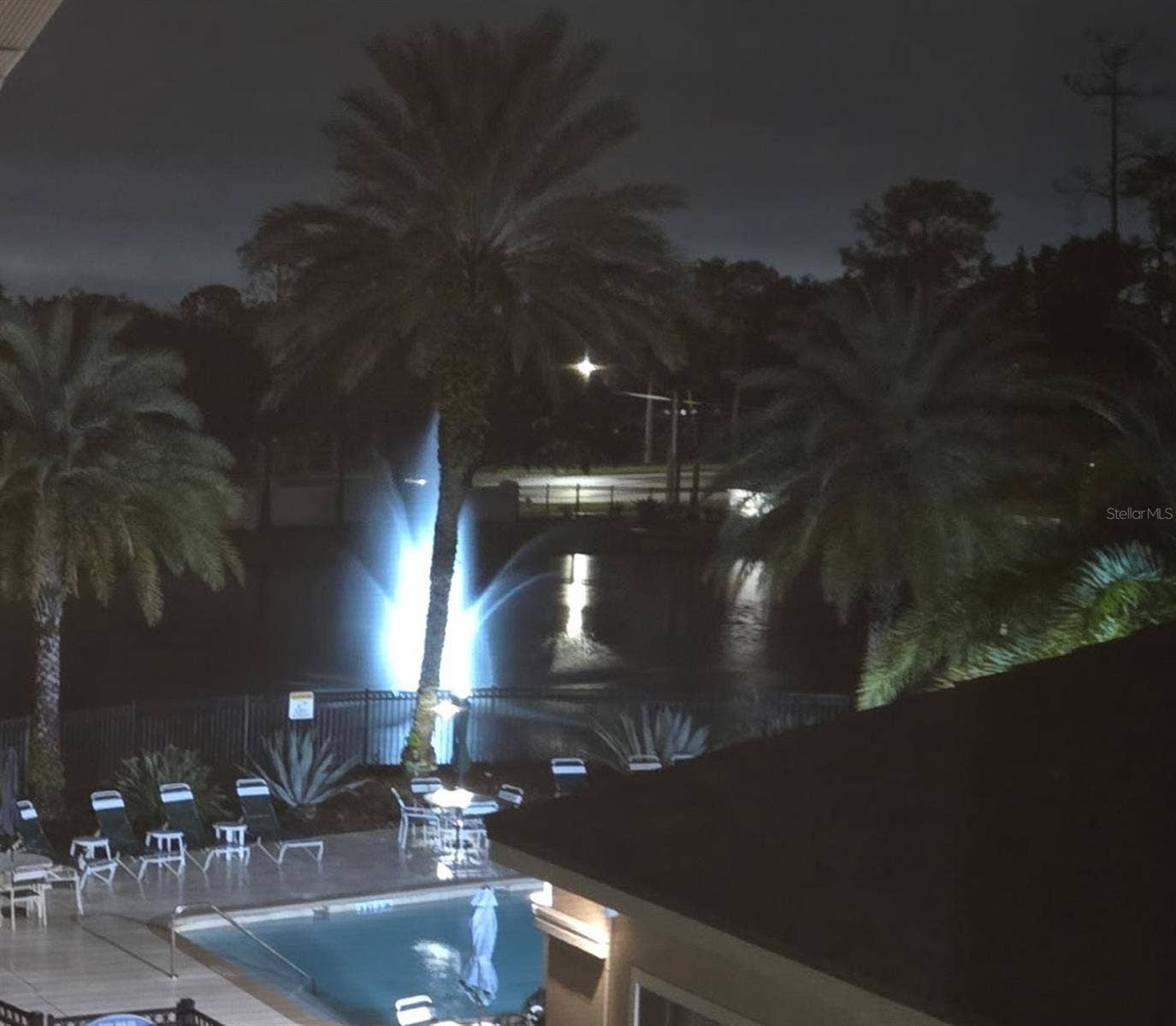 Night view of community pool and pond fountain from balcony