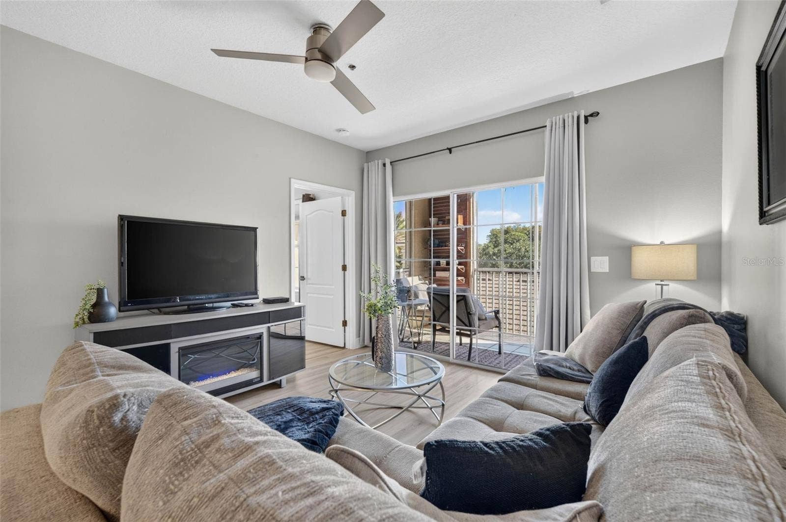 Living room with TV, ceiling fan and balcony door