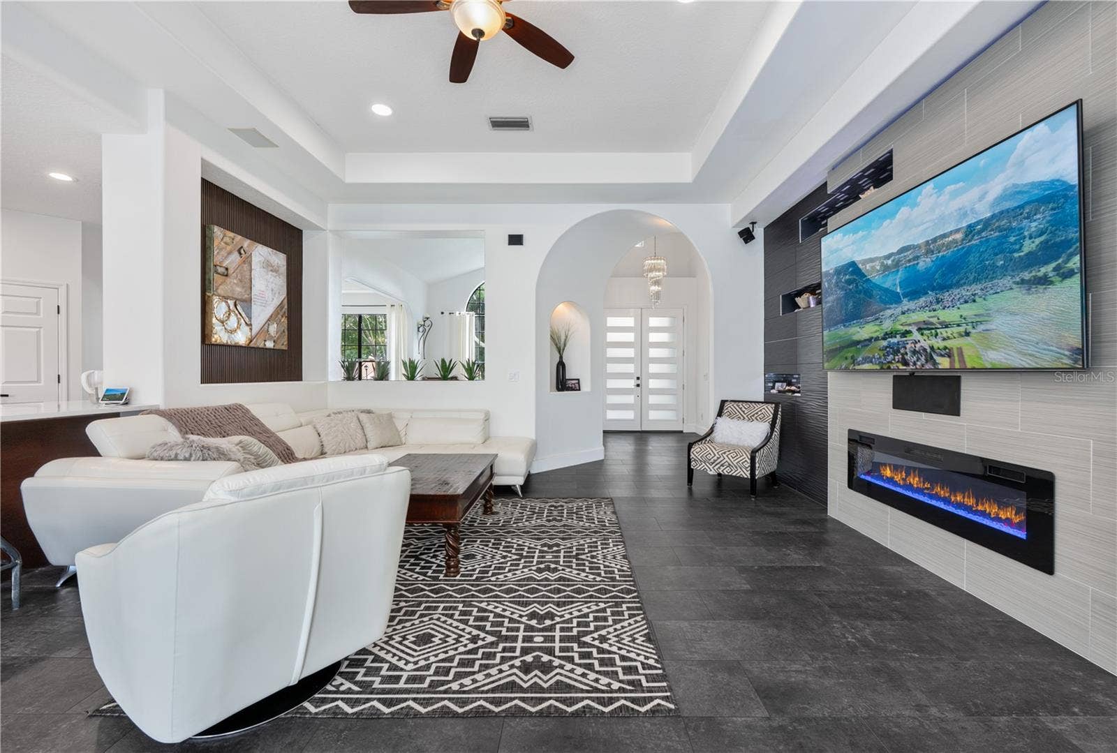 1854 VISTA ROYALE BOULEVARD, Orlando, FL 32835 Spacious family room featuring custom wall treatments, recessed display niches with LED lighting and decorative mosaic tile, and a cozy fireplace.