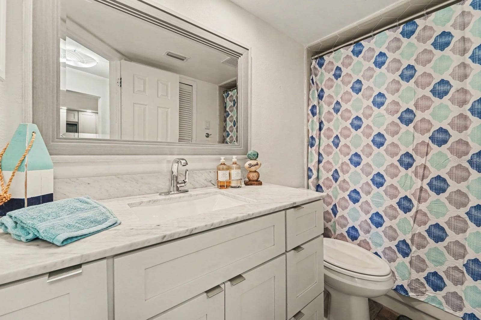143 CROWN POINT CIRCLE, #143, Longwood, FL 32779 Secondary bathroom with marble-look vanity, spacious mirror, patterned shower curtain