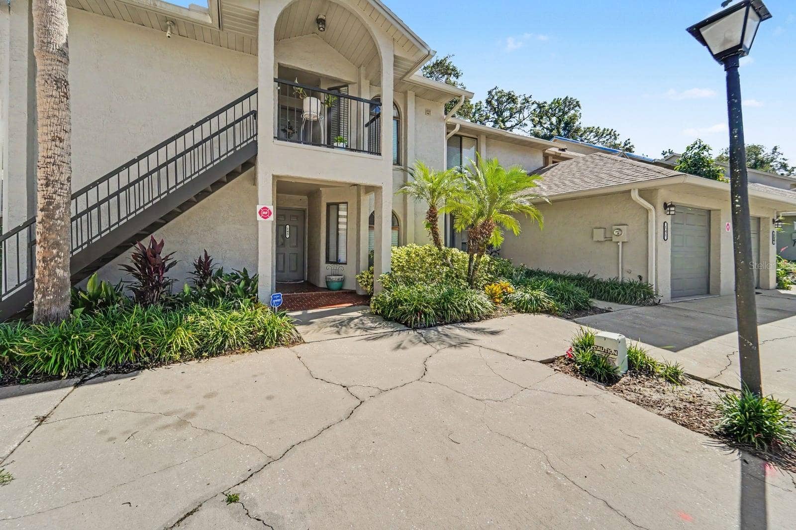 143 CROWN POINT CIRCLE, #143, Longwood, FL 32779 Elevated Entry with Black Railing and Lush Landscaping Frame Home Entrance