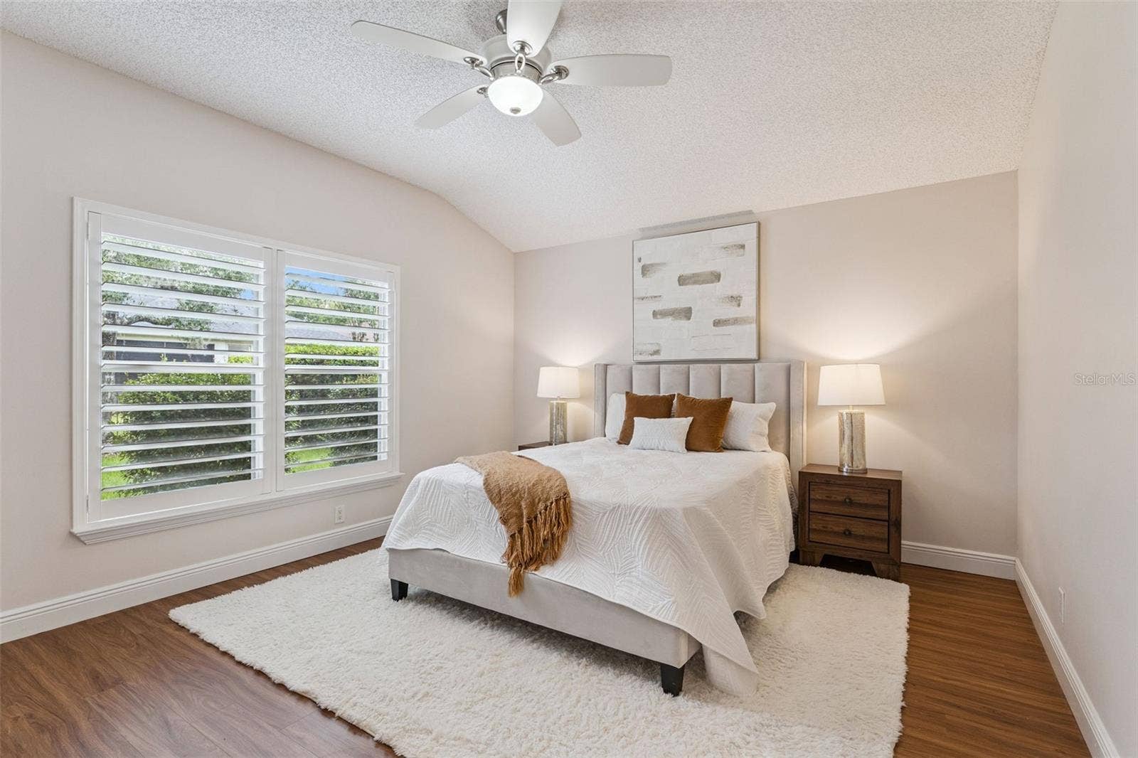 15'6" x 12'6" Primary Bedroom w/ a laminate floor, ceiling fan & Plantation style shutters
