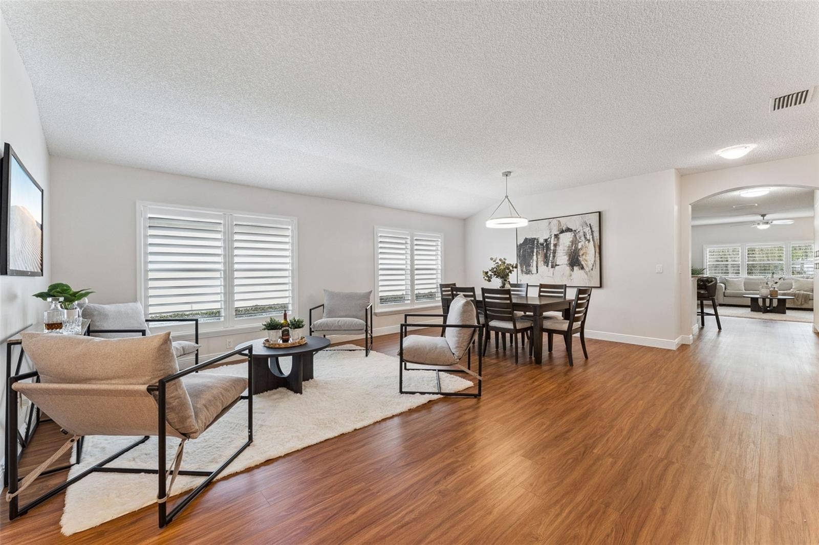 View of the Living & Dining Room areas w/ Plantation style shutters & a laminate floor