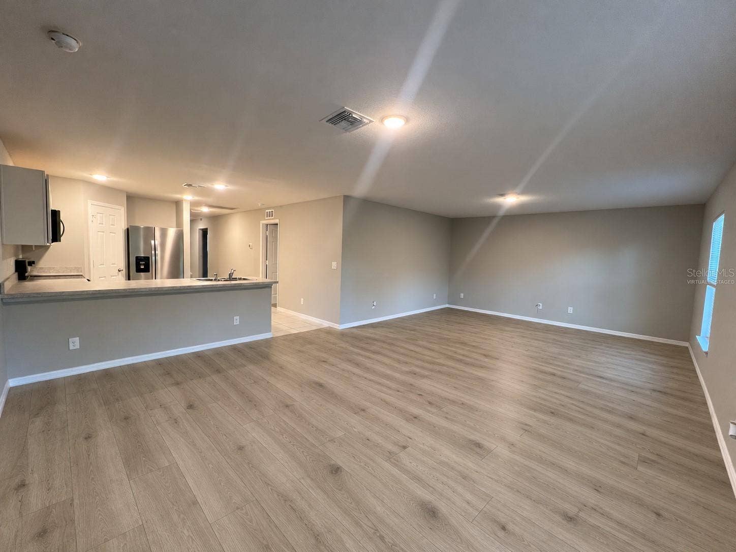 3404 61ST STREET W, Lehigh Acres, FL 33971 Living room and kitchen virtually staged: planned laminate flooring.