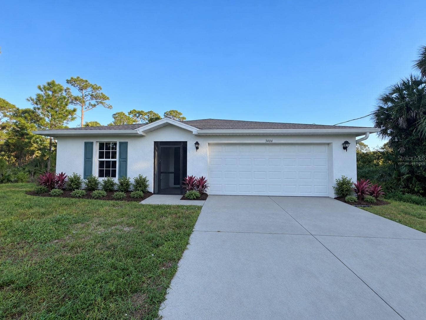 3404 61ST STREET W, Lehigh Acres, FL 33971 Front exterior virtually staged: proposed landscaping and concrete-gray driveway finish.