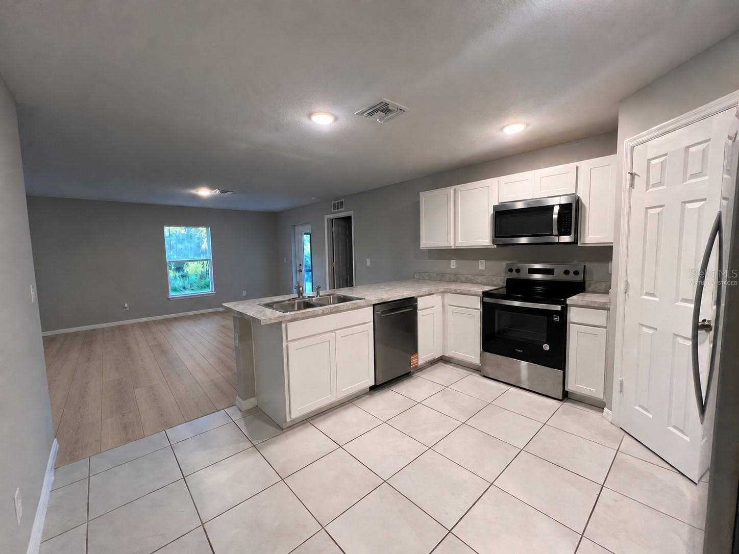 3404 61ST STREET W, Lehigh Acres, FL 33971 Kitchen and living area virtually staged: planned laminate flooring.