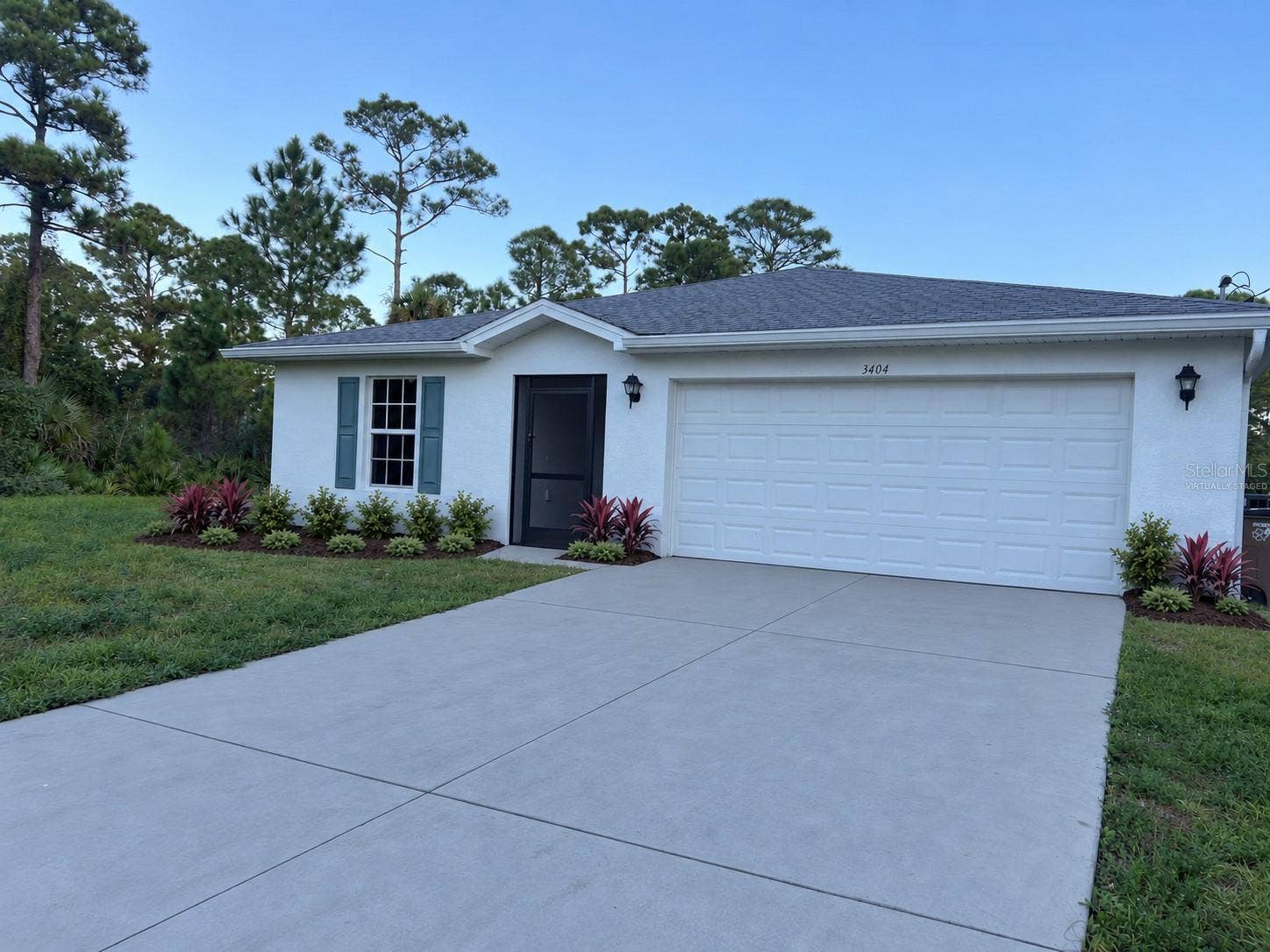 3404 61ST STREET W, Lehigh Acres, FL 33971 Front exterior virtually staged: proposed landscaping and concrete-gray driveway finish.