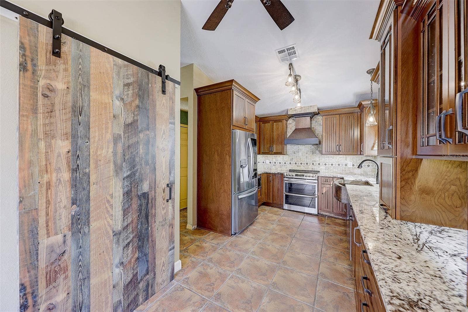 The custom-renovated kitchen, completed in 2021, is a standout feature, offering custom cabinetry with soft-close doors and drawers, polished granite countertops with natural edges, a custom tile backsplash, a copper undermount sink, and a touch-operated faucet with an integrated pot-filler feature. Additional details include a solid-wood barn door pantry, a built-in cabinet with antique glass doors and interior lighting, under-cabinet lighting, and quality appliances, including a French-door refrigerator, extra-quiet Bosch dishwasher, microwave installed in the lower cabinetry, and LG double oven, complemented by a full-size copper overhead range exhaust hood.