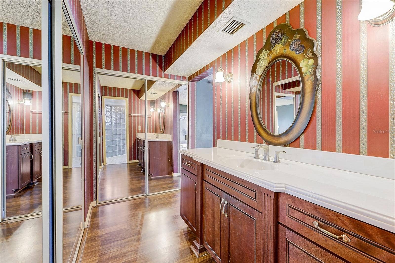 **The primary bedroom and bathroom have been pained since these pictures** The downstairs primary suite offers a private, walled courtyard, direct access to the pool deck, and custom closet shelving installed in 2025. The primary bathroom, renovated in 2020, features a custom-tiled walk-in shower, rain-style showerhead, glass-block divider, and a high-set triple-pane window.