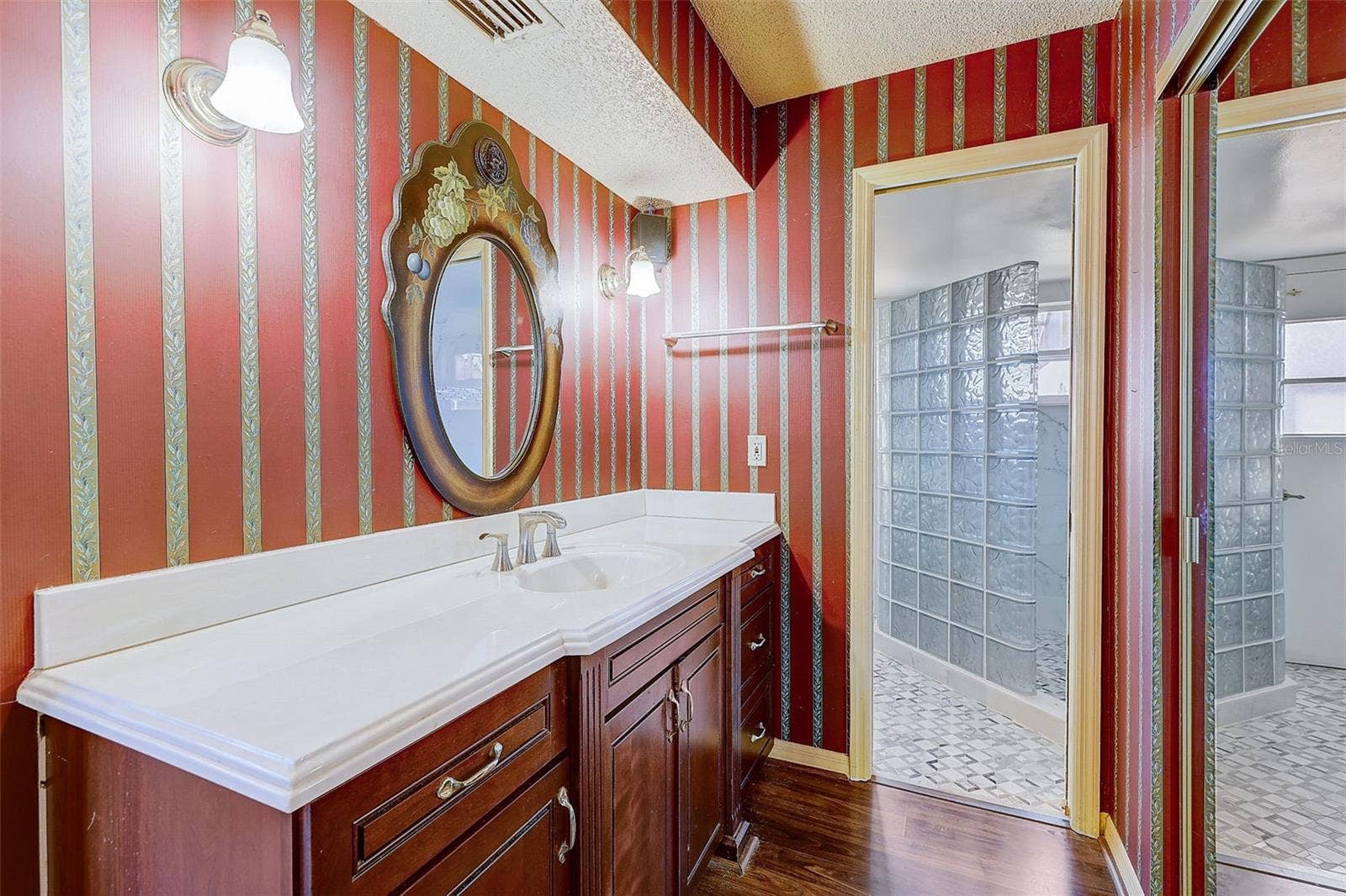 **The primary bedroom and bathroom have been pained since these pictures** The downstairs primary suite offers a private, walled courtyard, direct access to the pool deck, and custom closet shelving installed in 2025. The primary bathroom, renovated in 2020, features a custom-tiled walk-in shower, rain-style showerhead, glass-block divider, and a high-set triple-pane window.