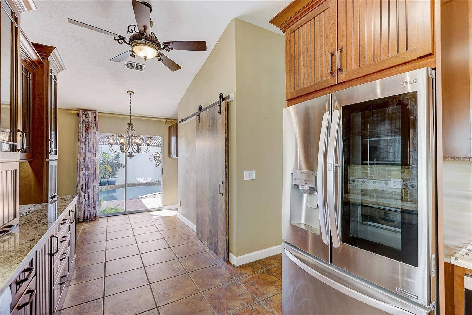 The custom-renovated kitchen, completed in 2021, is a standout feature, offering custom cabinetry with soft-close doors and drawers, polished granite countertops with natural edges, a custom tile backsplash, a copper undermount sink, and a touch-operated faucet with an integrated pot-filler feature. Additional details include a solid-wood barn door pantry, a built-in cabinet with antique glass doors and interior lighting, under-cabinet lighting, and quality appliances, including a French-door refrigerator, extra-quiet Bosch dishwasher, microwave installed in the lower cabinetry, and LG double oven, complemented by a full-size copper overhead range exhaust hood.