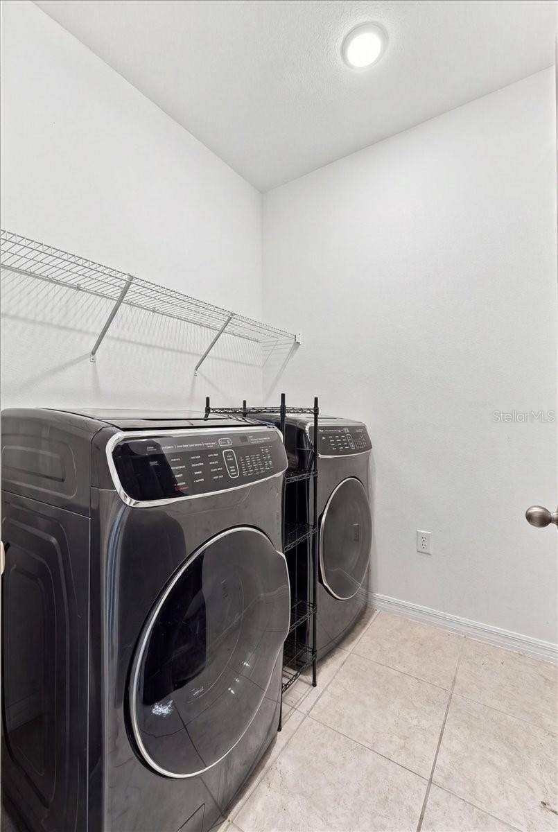 Dedicated indoor laundry room featuring convenient shelving and space for a full-size washer and dryer.