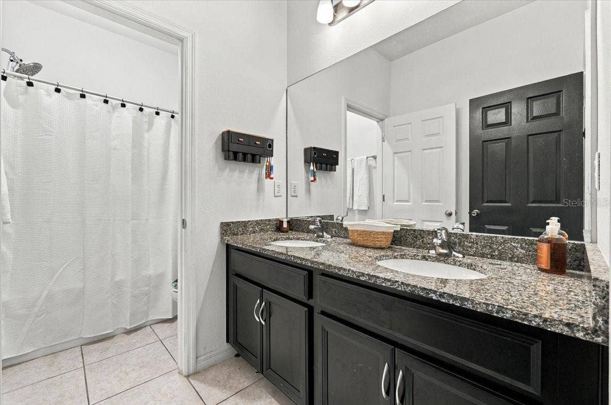 Full secondary bathroom featuring a double-sink vanity, generous countertop space, and a tub/shower combination.