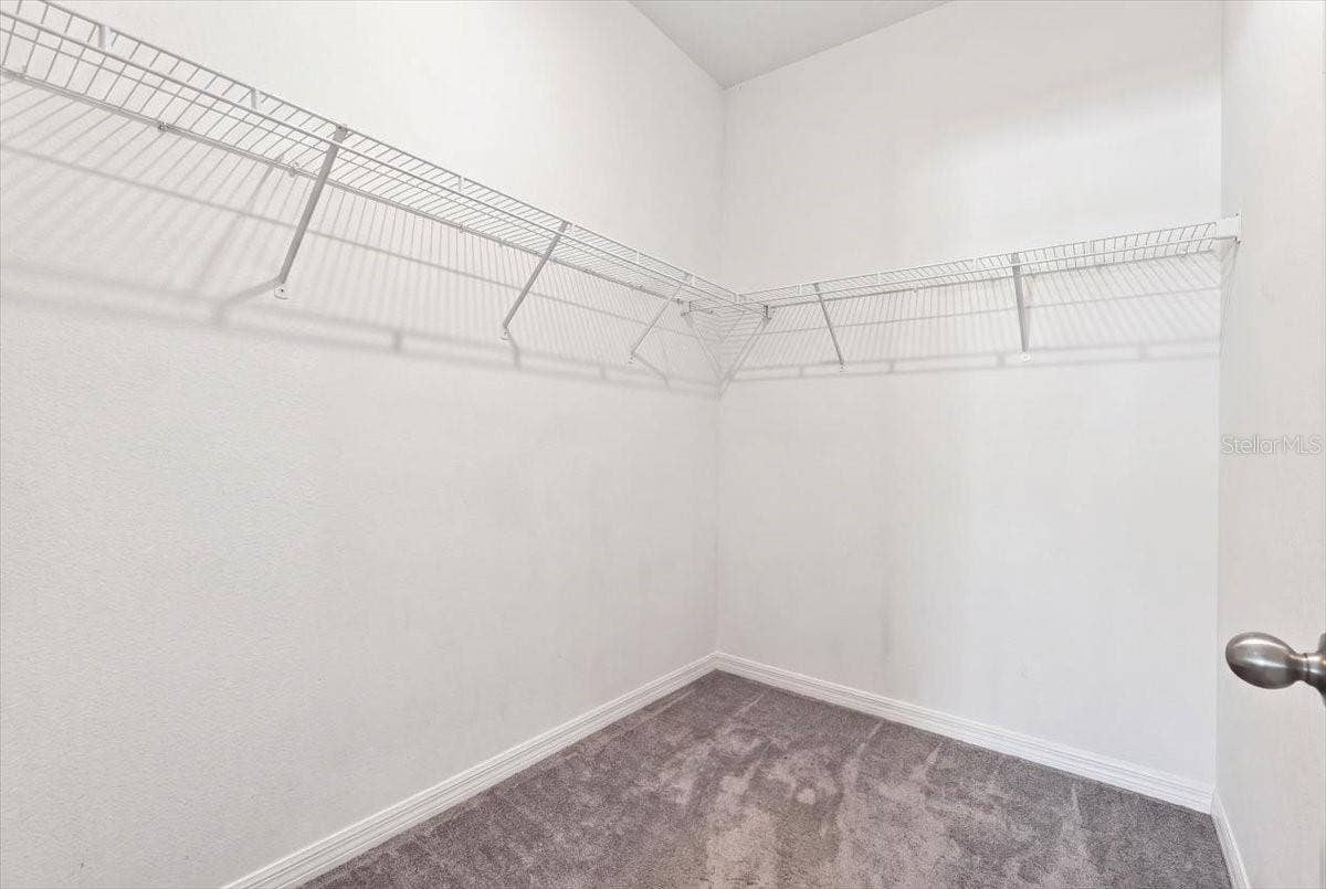 Spacious primary bedroom walk-in closet featuring ample shelving and hanging space for storage and organization.